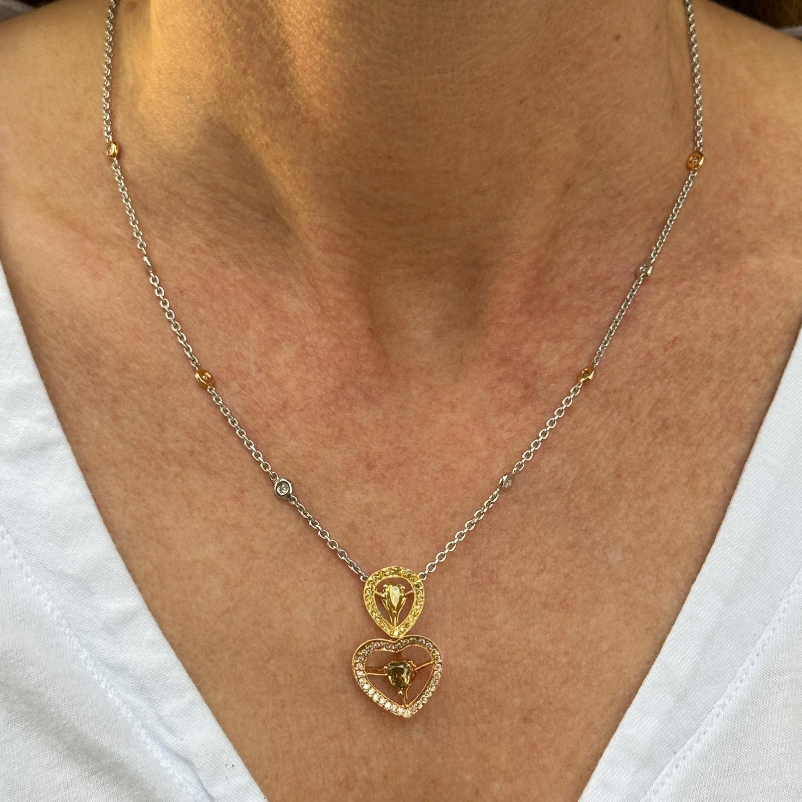 Colorful diamond heart pendant drop necklace crafted in 18 karat white and rose gold. The necklace features an approximately .50  carat pear shape champagne diamond, a .20 carat pear shape yellow diamond, and another .53 CTW of white and yellow