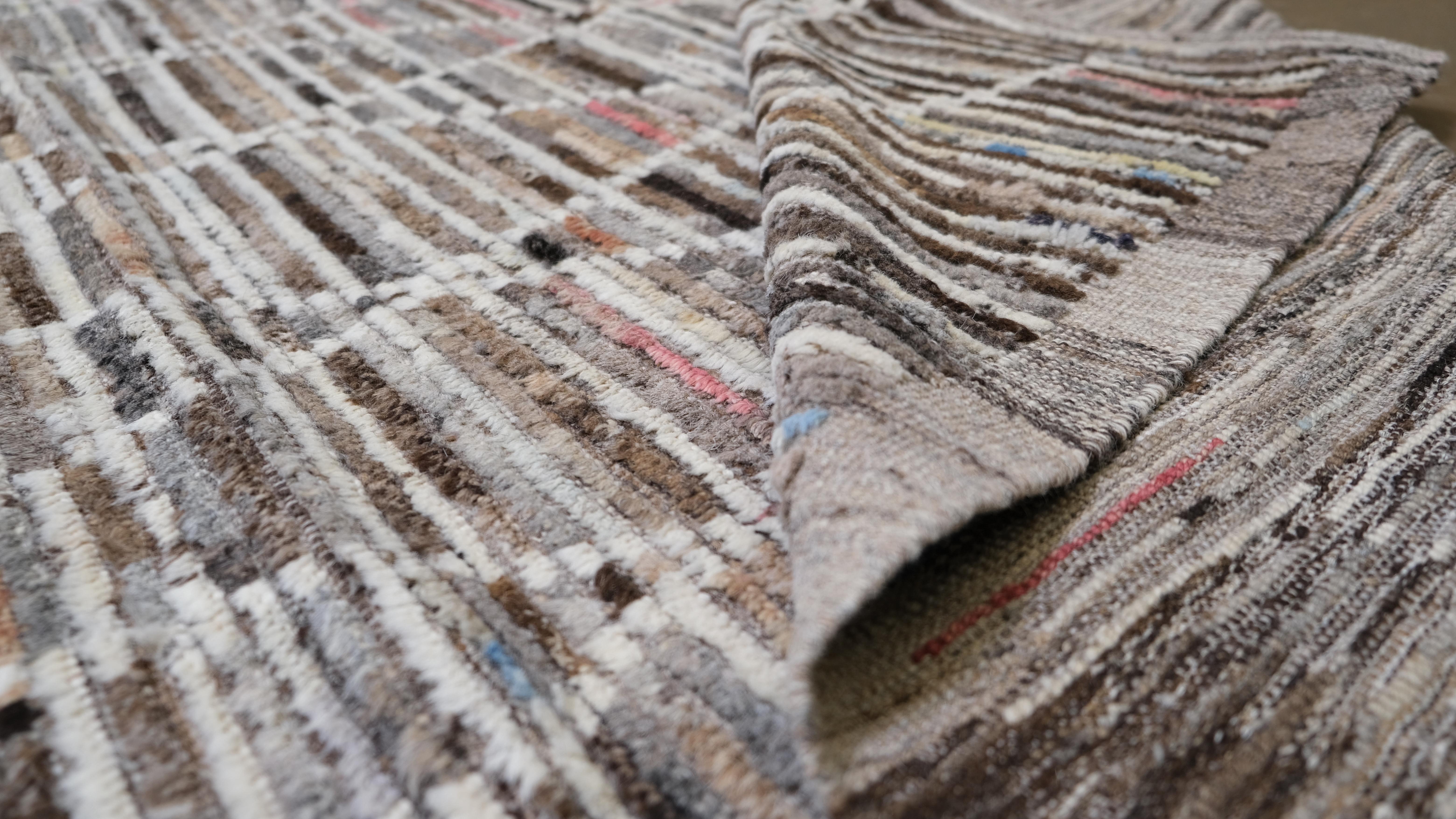 Dieser atemberaubende handgeknüpfte Wollteppich ist eine einzigartige Mischung aus zeitgenössischer Kunst und traditioneller Handwerkskunst. Mit seinem verschlungenen geometrischen Gittermuster, das einen reichhaltigen, mehrfarbig gestreiften
