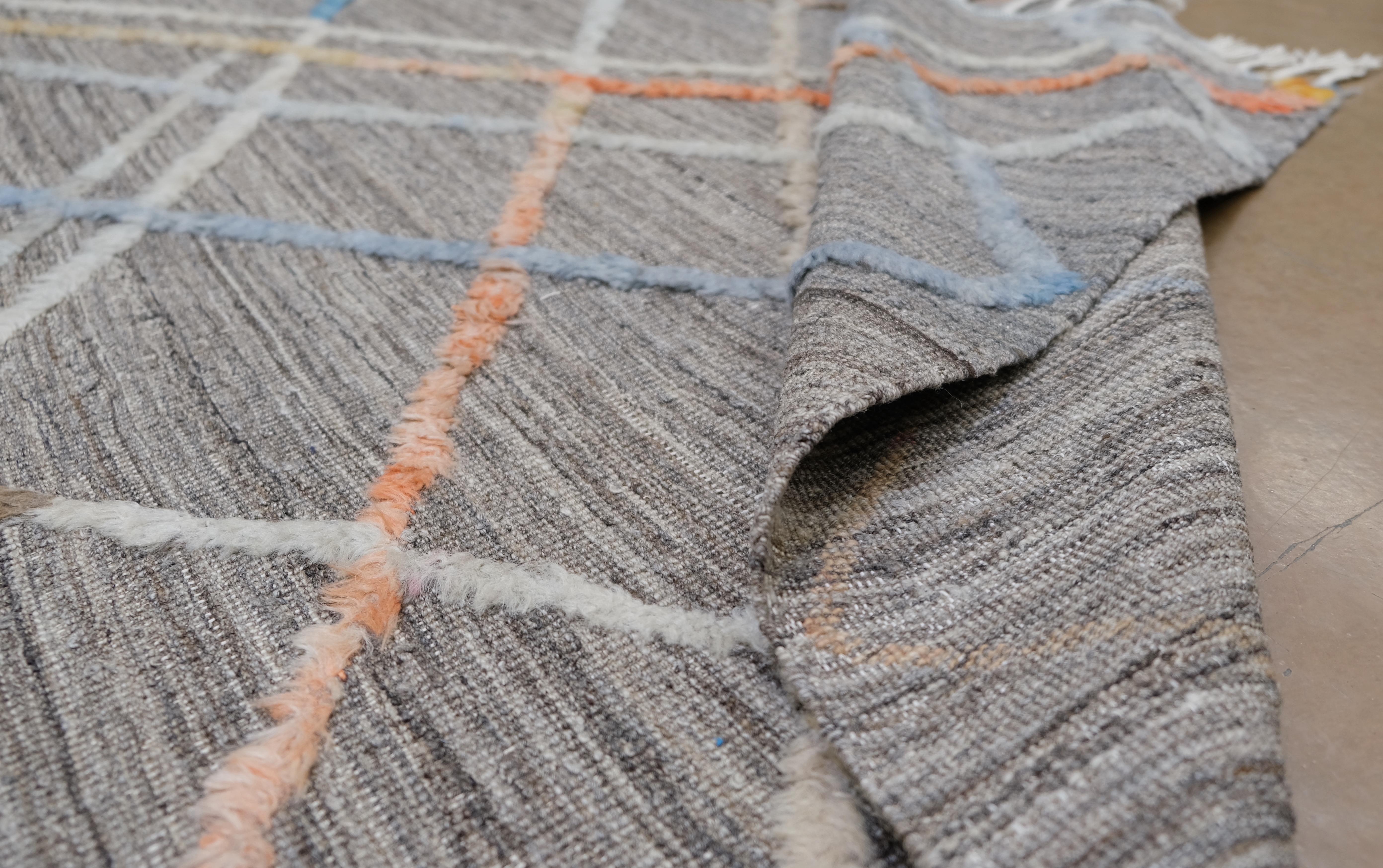 Con un intrincado dibujo entrecruzado multicolor sobre una base gris marrón neutra, esta alfombra destila sofisticación moderna a la vez que añade un toque vibrante a tu decoración. El dinámico juego de líneas naranjas, azules, blancas y beige crea