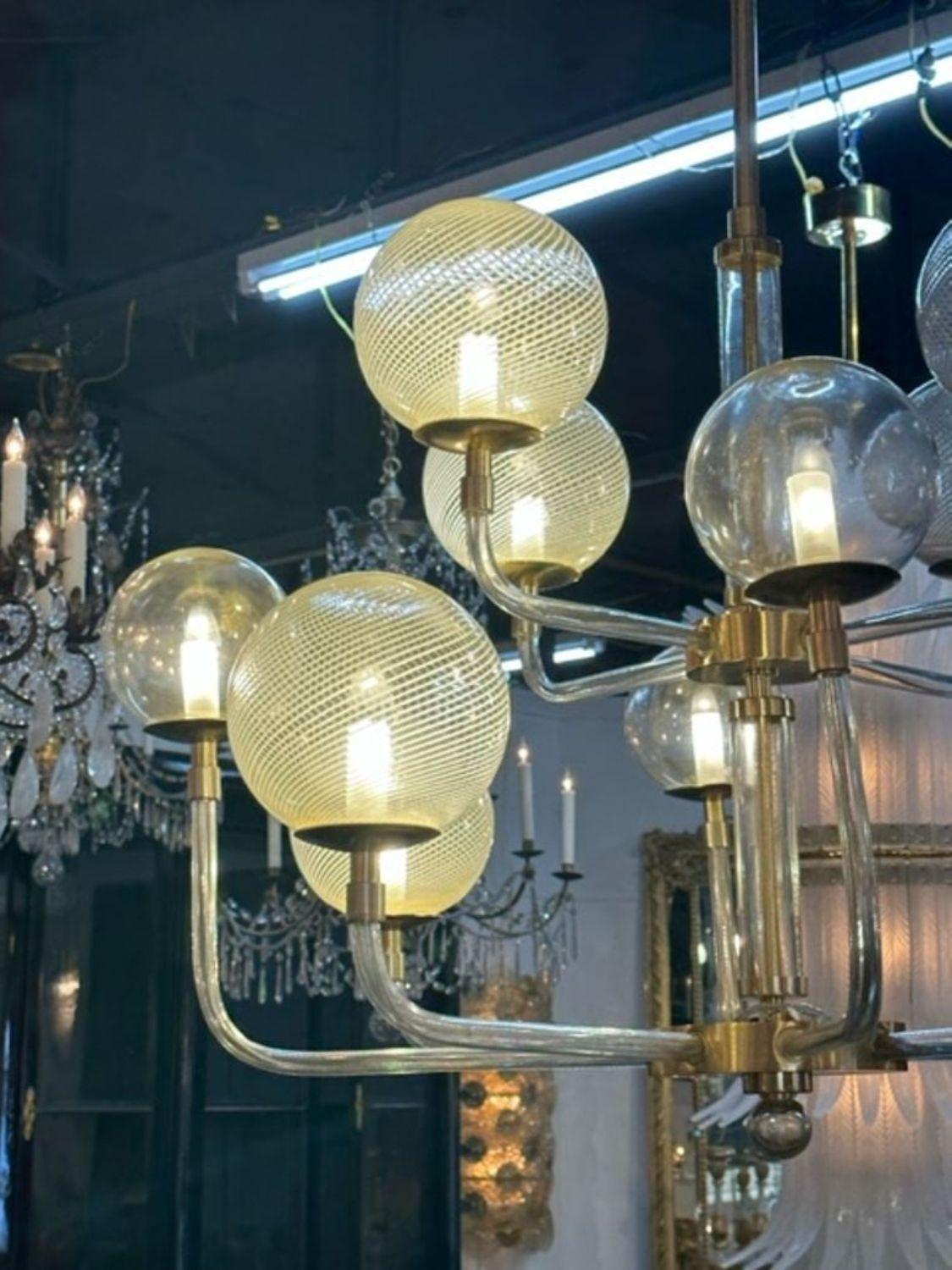 Modern Murano glass and brass globe chandelier. Lovely pattern on the globes along with beautiful glass arms and brass features. Creates an impressive look!