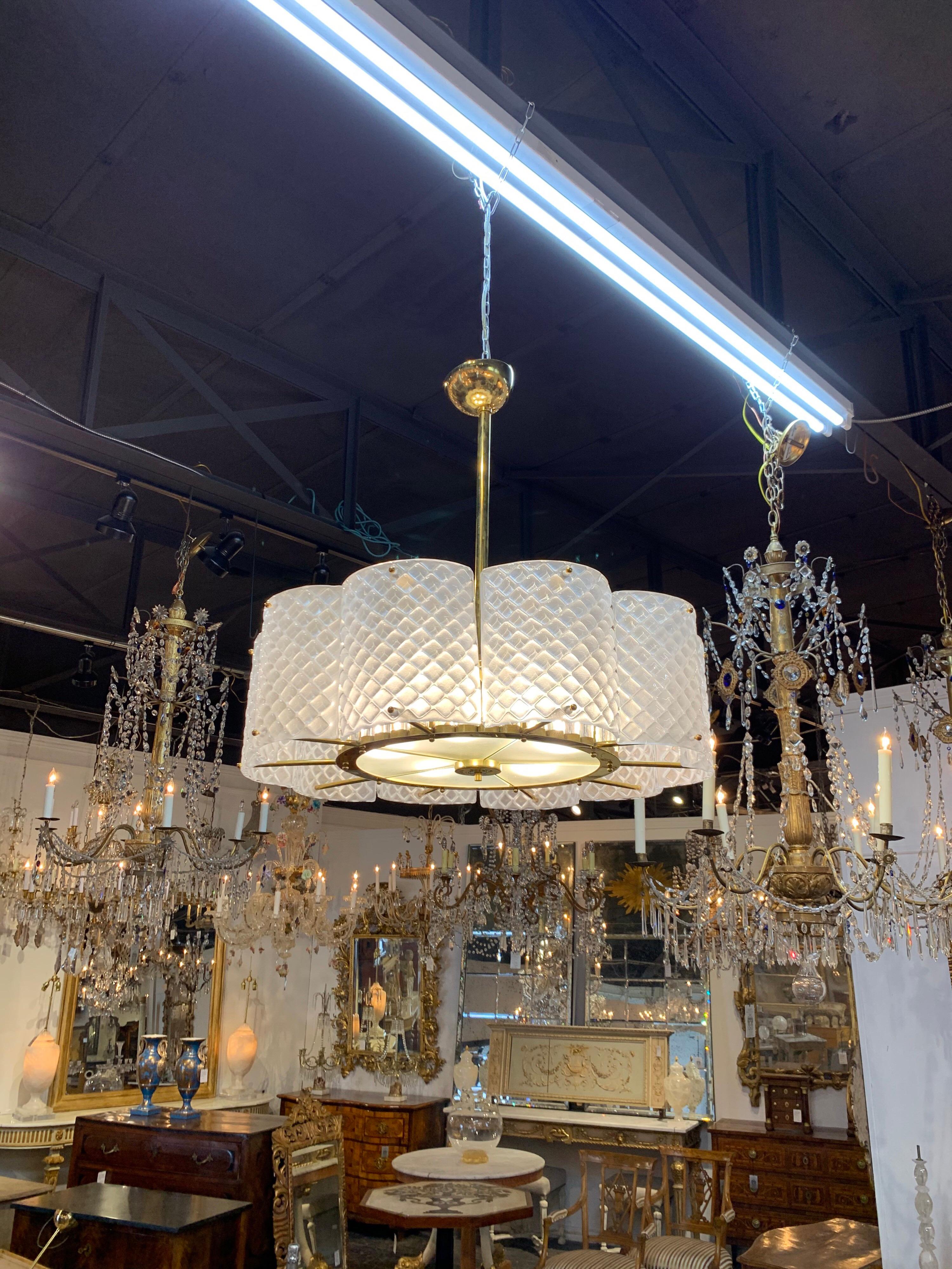 Stunning Murano glass and brass chandelier. Very pretty sections of white toned Murano glass with brass base. Notice the cylinders of glass inside the fixture adding additional interest. A great look for a modern home!