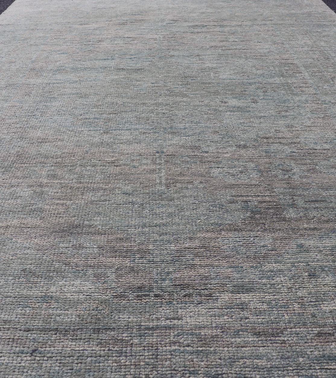 Misure: 6'0 x 9'3. 
Tappeto moderno di tipo Oushak in lana con disegno sub-geometrico nei toni del verde e della terra
Questo moderno tappeto indiano è stato annodato a mano in lana e presenta un disegno sub-geometrico all-over nei toni del verde e