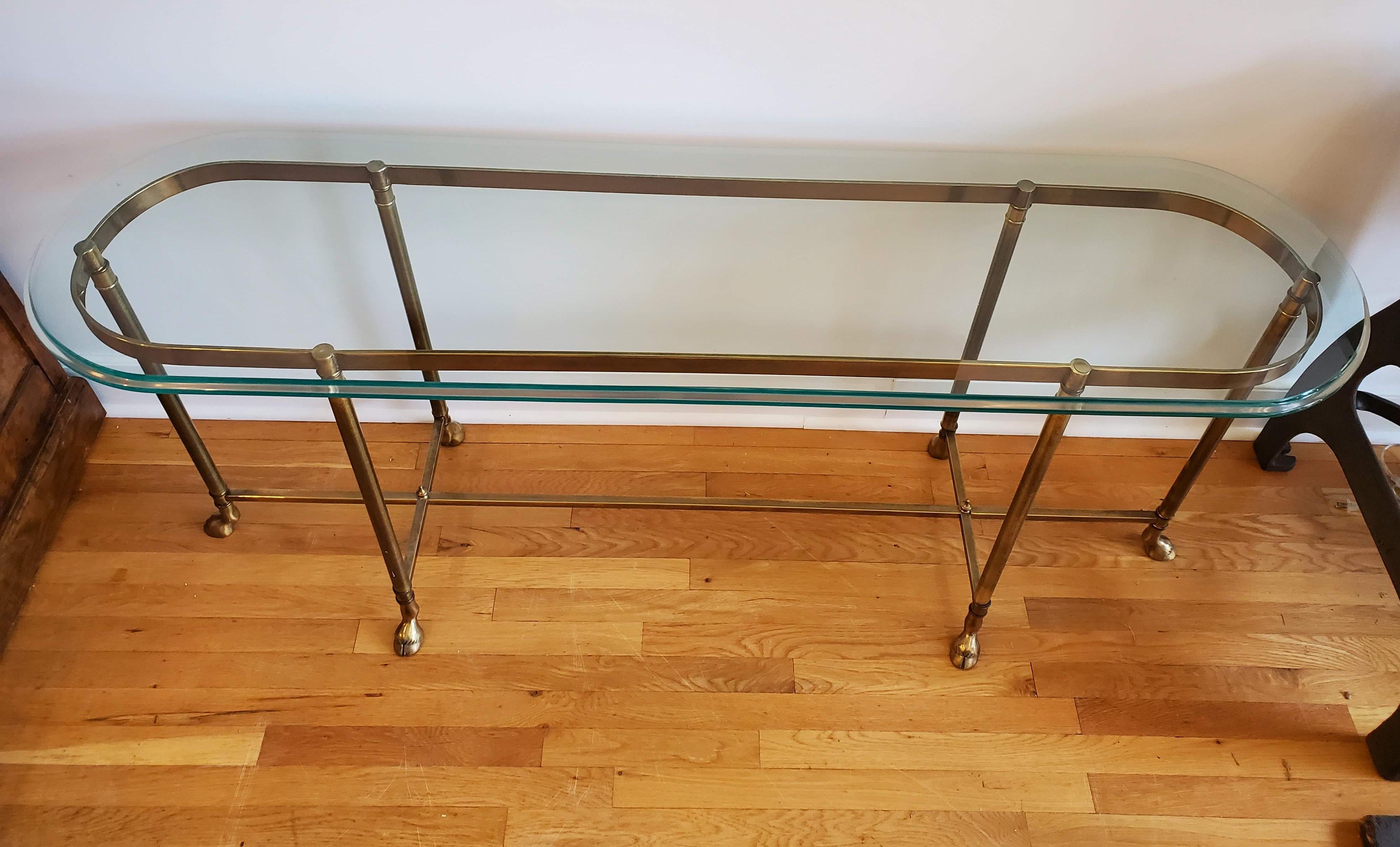 Modern narrow sofa table. Made of brass. Six legs with decorative “hoof” feet with the original glass top.
Measures: 27” H 62” W 18” D.
 