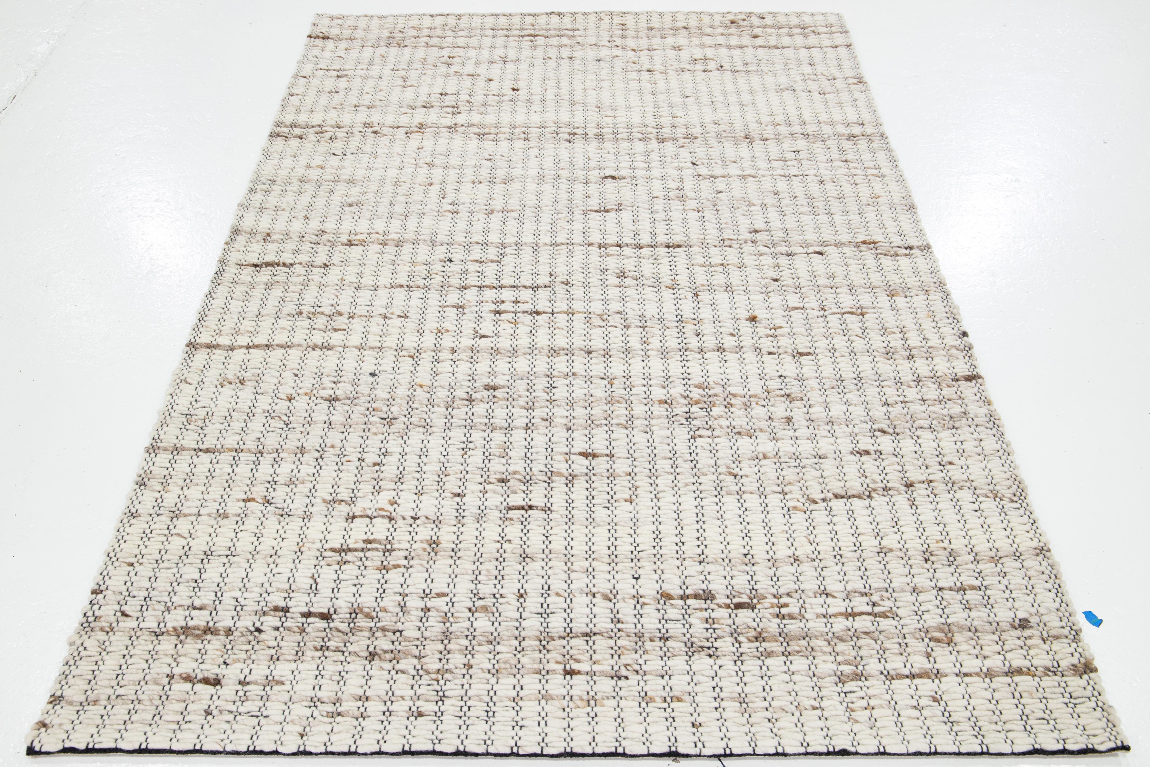 Dieser schöne handgewebte Wollteppich aus Filz ist Teil unserer Westport Collection'S. Es hat ein beiges Feld mit braunen und grauen Akzenten in dem geometrischen Muster.

Dieser Teppich misst 5' x 8'.

Kundenspezifische Farben und Größen sind auf