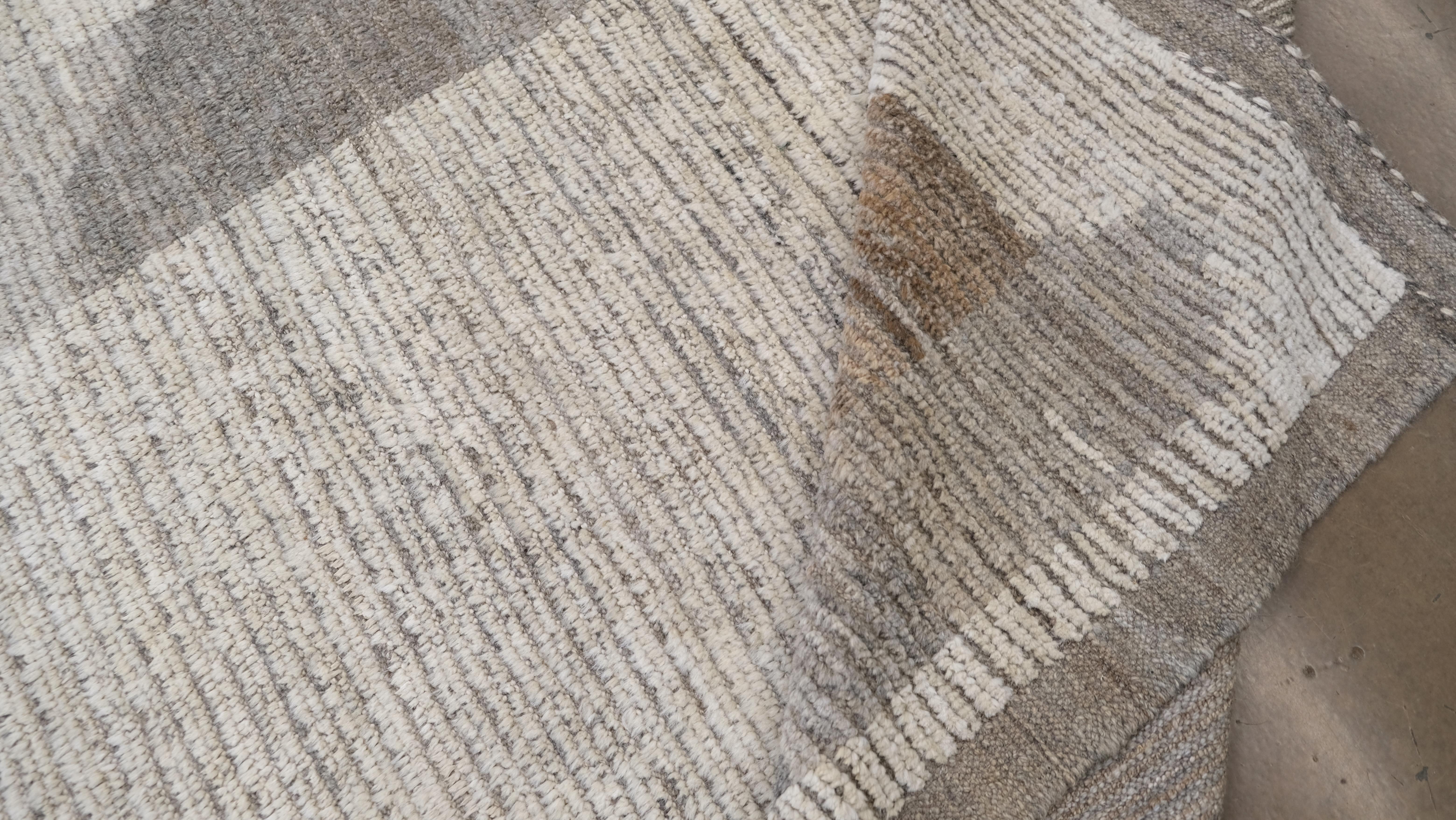 Dieser handgeknüpfte Wollteppich verleiht Ihrer Einrichtung einen zeitlosen Charme. Mit seinem faszinierenden linearen, abstrakten Design in neutralen Beige-, Grau- und Erdbrauntönen strahlt dieser Teppich eine zeitgenössische Ästhetik aus, die