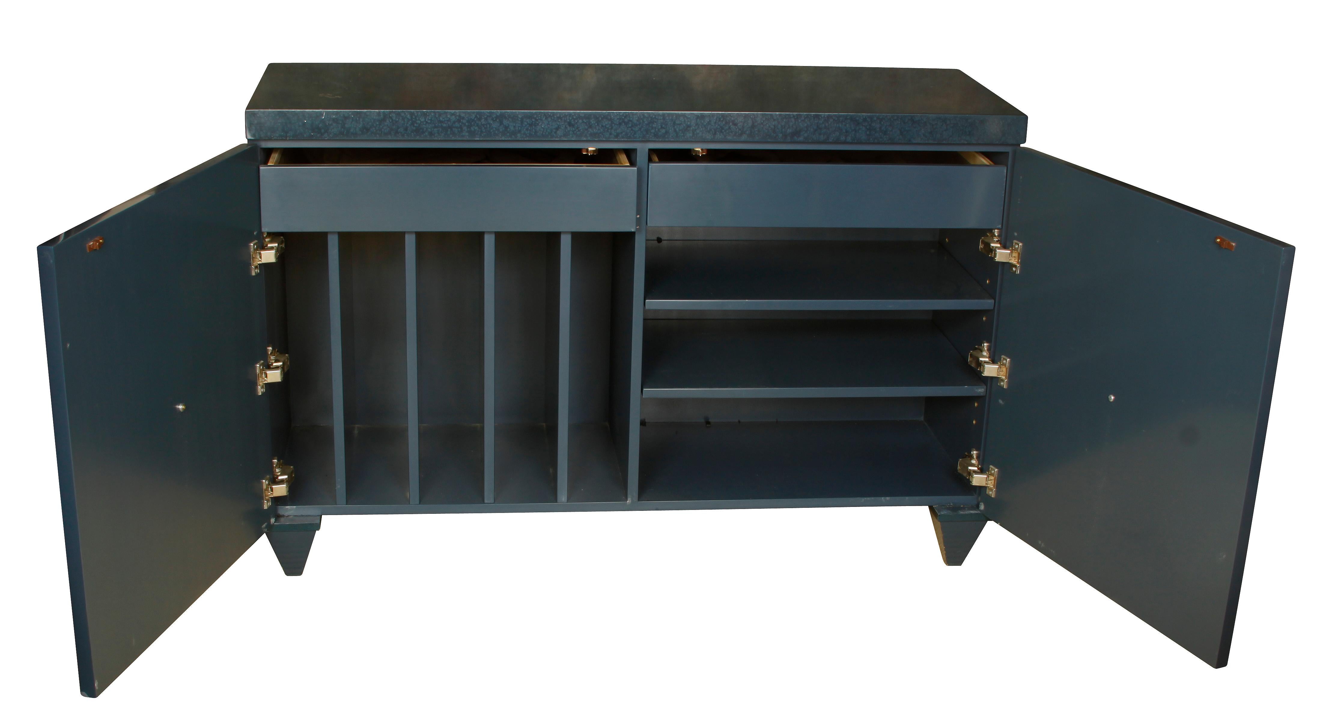 Modern serving cabinet in lacquered blue wood with contemporary brass knobs. Two doors open to reveal two drawers, vertical storage and three drawers.