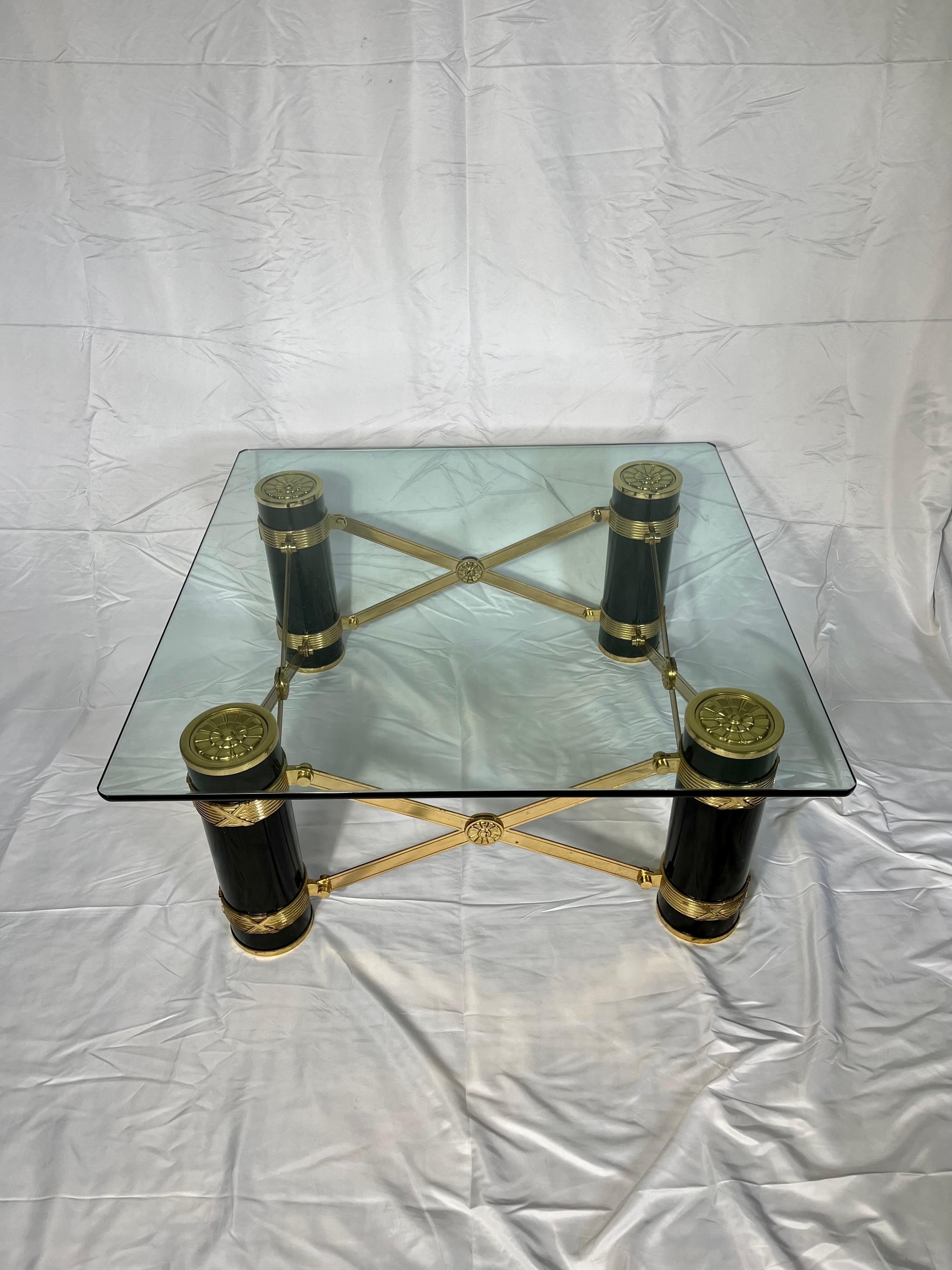 Beautiful and rare coffee table. Modern Neoclassical design in the manner of Mastercraft with spot on attention to detail. Black columns capped with embossed brass florets. each column has a banding and is attached with brass cross stretchers with