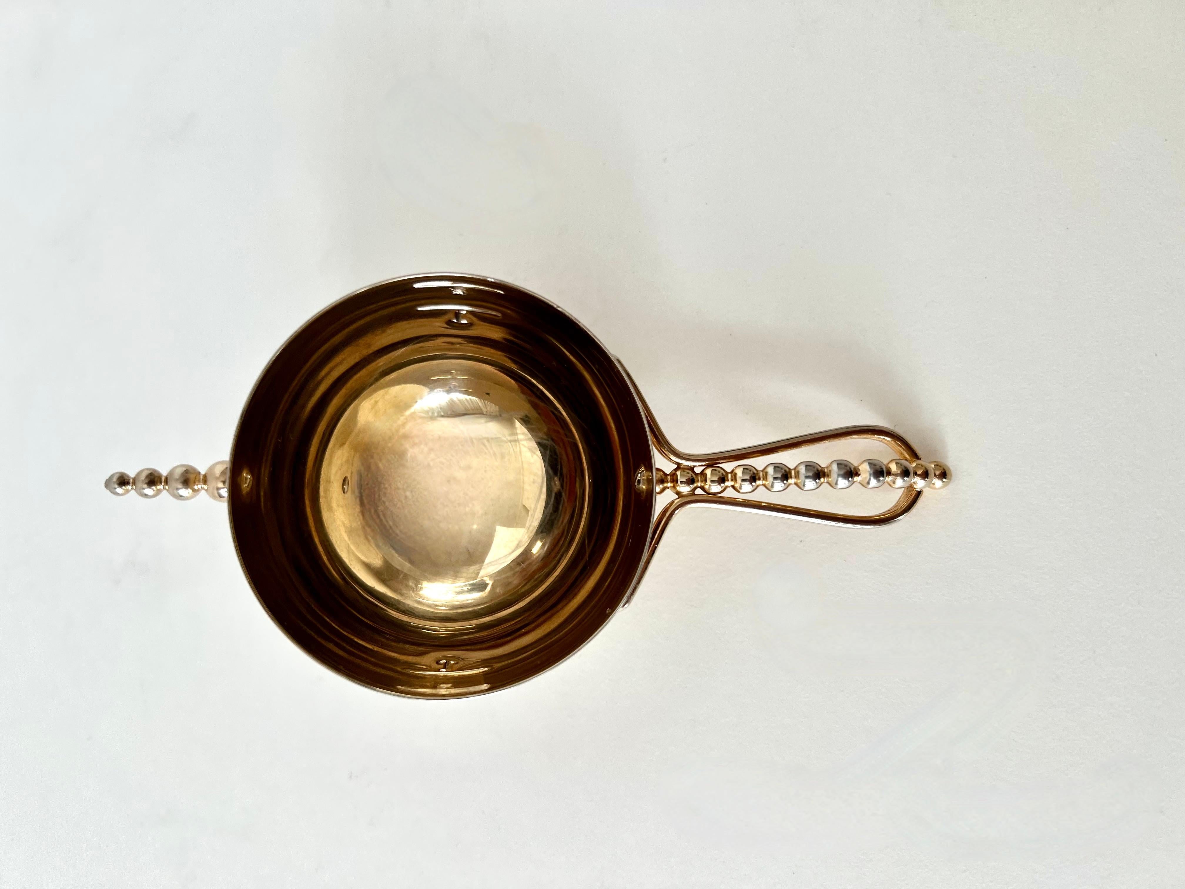 Un jigger muy clásico y ultramodernista con dos medidas: la elegante pieza está diseñada de forma muy arquitectónica con el asa de cuentas y el detalle que lleva las cuentas a la parte superior, al estilo de Georg Jensen.

Sentado en un vaso, vierte