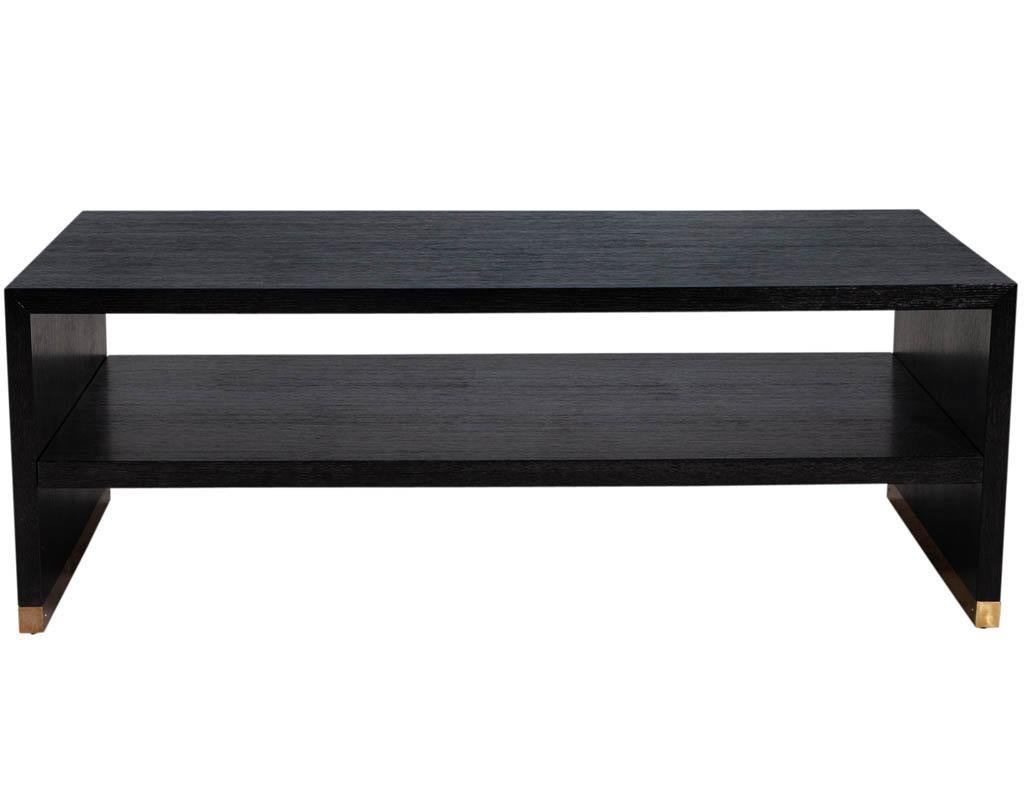 Modern oak 2 tier coffee table. Finished in a satin cerused black with brass base.
Price includes complimentary curb side delivery to the continental USA.