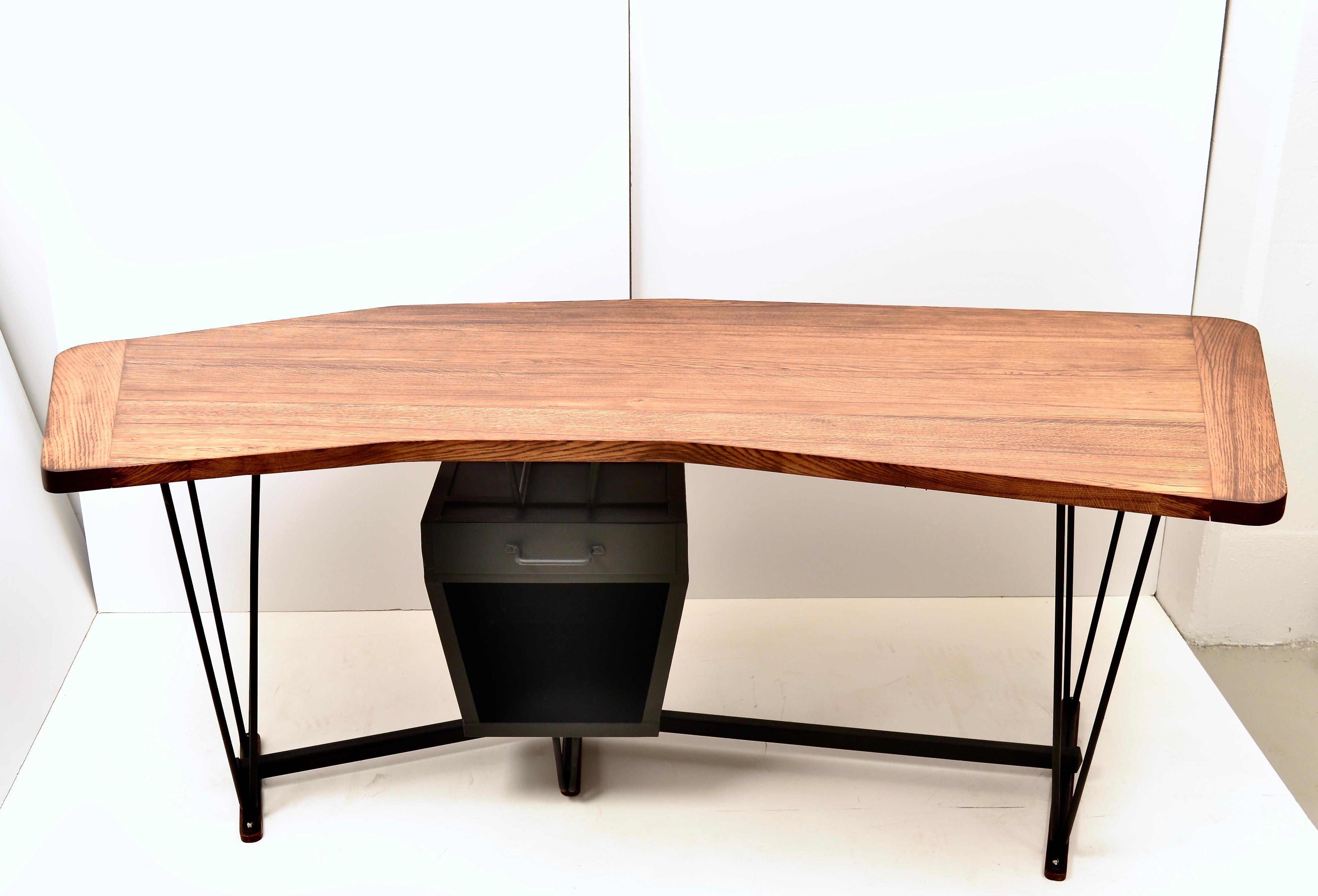 A real statement piece, this French early modernism desk features a boomerang shaped top in solid oak. The distinctive iron base hold a storage space topped with a single drawer. The oak top has been newly restored using matte finish. The iron base