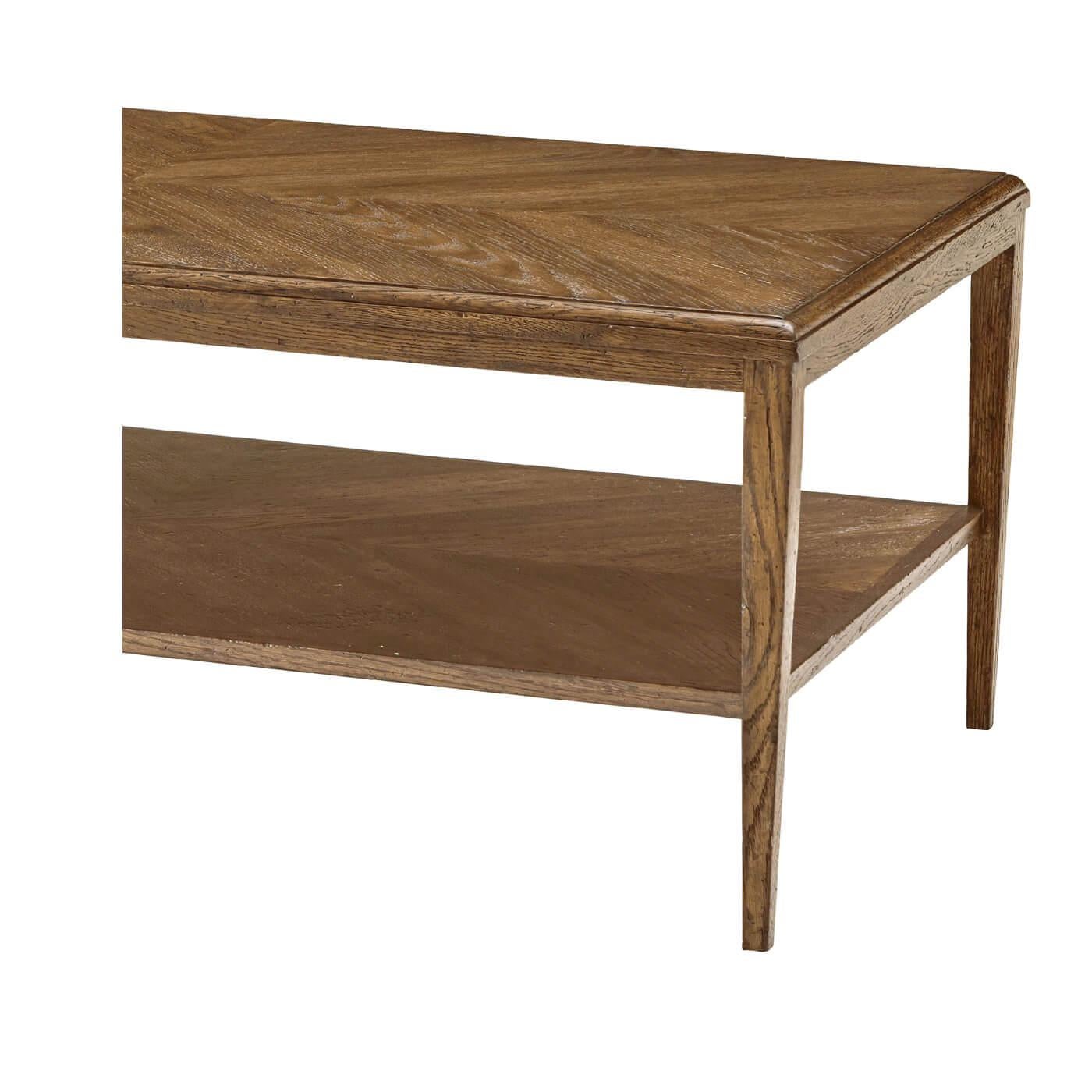 Une table basse moderne en chêne rustique clair. Cette table basse à deux niveaux présente un motif de parqueterie concentrique sur les niveaux supérieurs et inférieurs. Il repose sur des pieds en chêne effilés. 
Dimensions
50