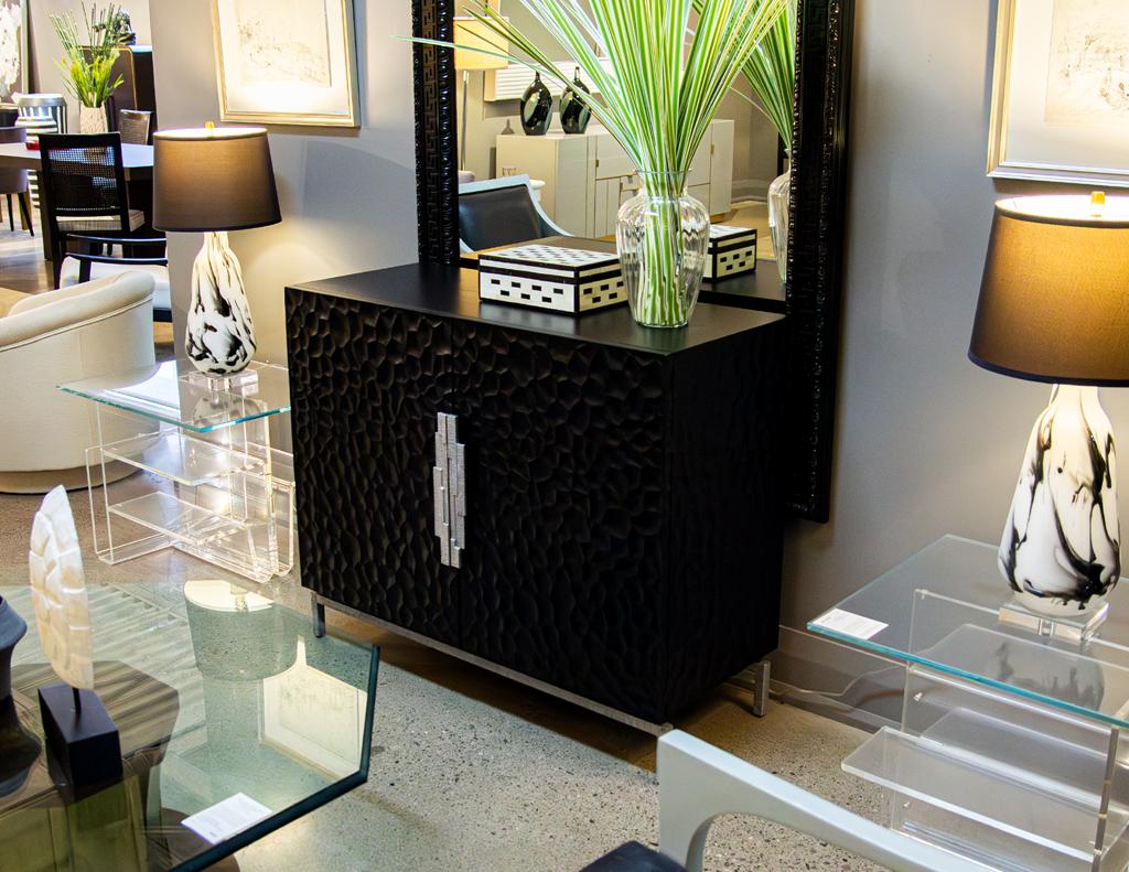 Indulge in the captivating allure of this exceptional modern oak sculpted cabinet, where artistry and functionality harmoniously intertwine. Its bold brutalist-inspired metal handles and platform, adorned in a brushed antiqued metal finish, exude an