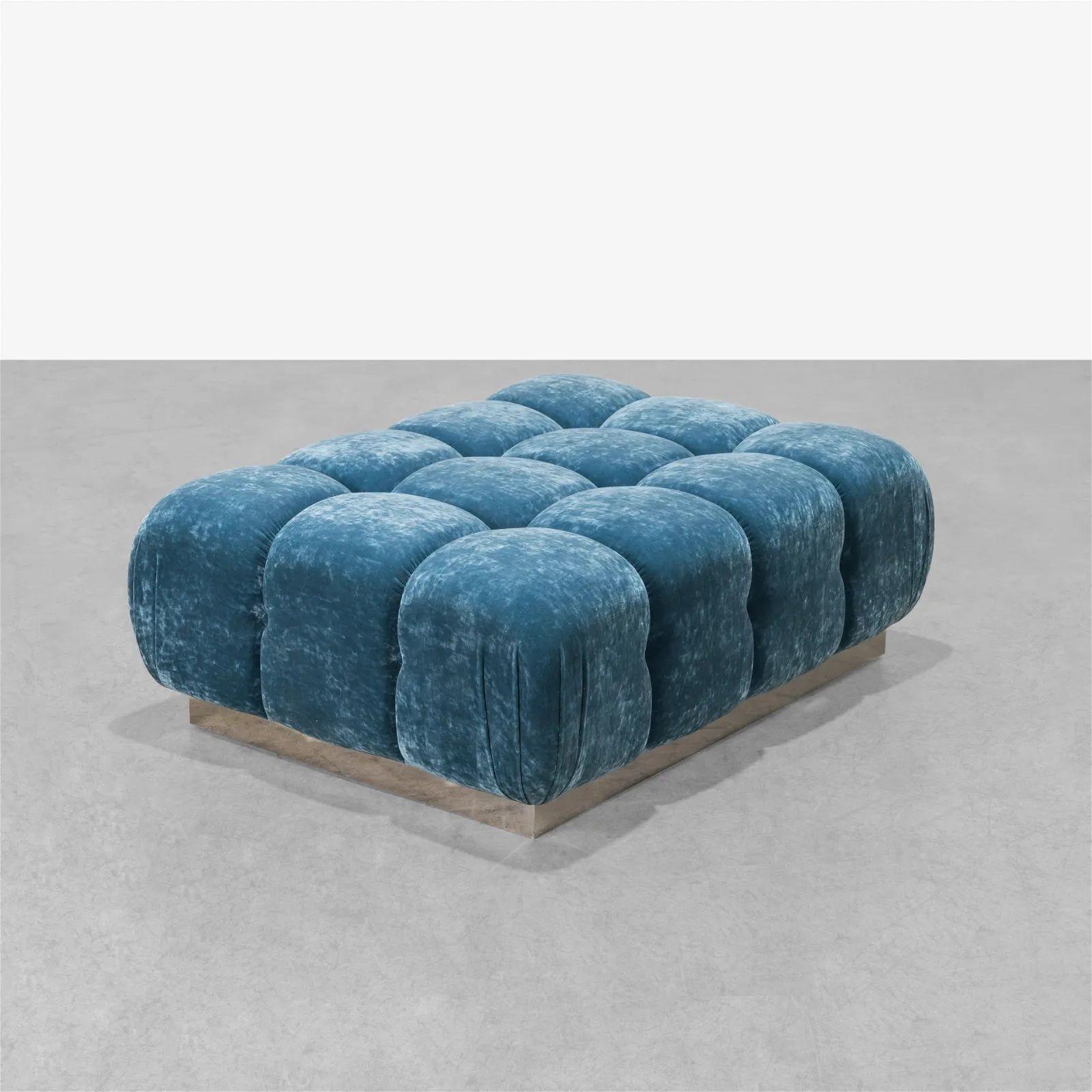 A modern ottoman with blue velvet design and a chrome base, made in a tufted design providing supreme comfort. The design is inspired by the opulence of 1970s Italian and American interiors. This example has a lustrous, light blue textured velvet
