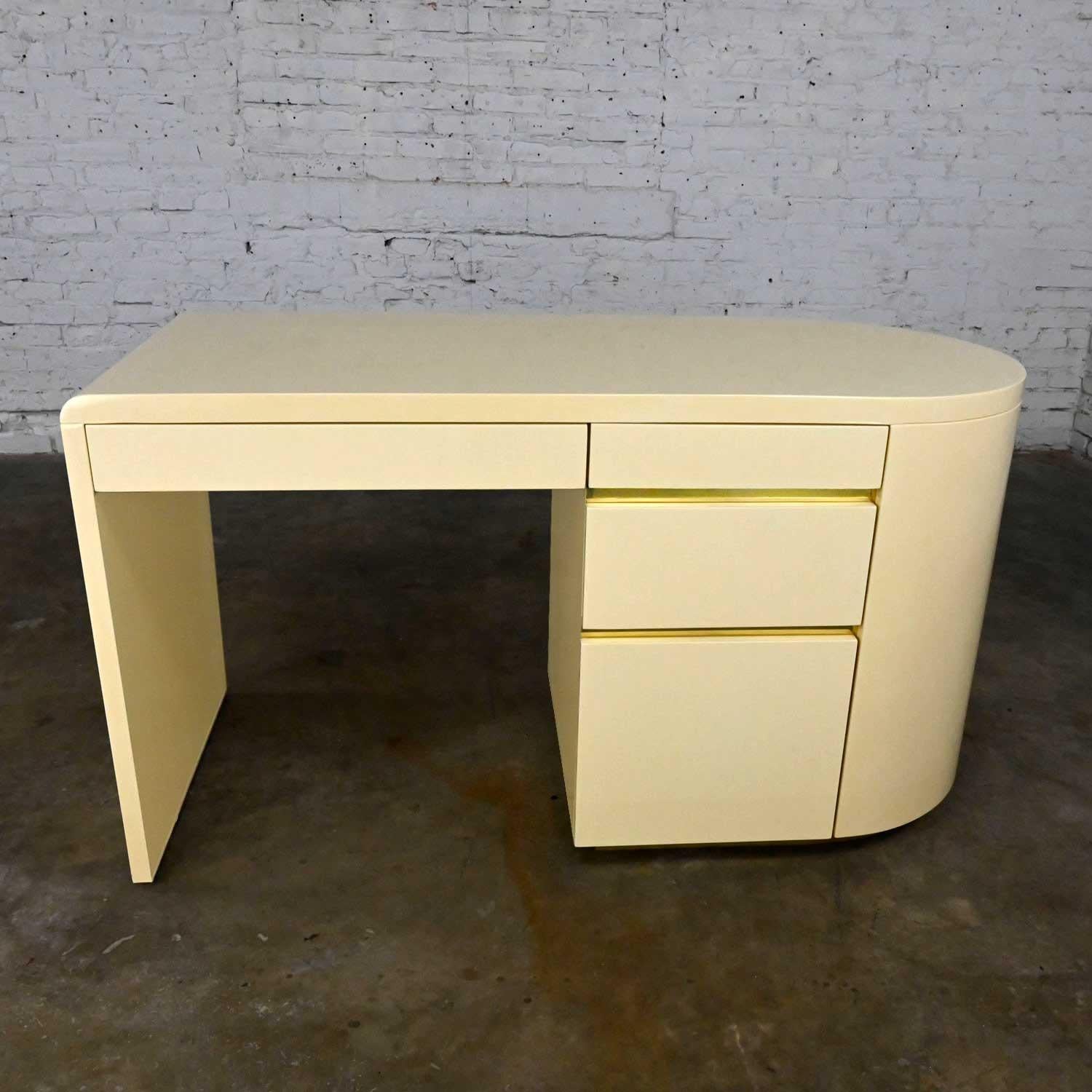 Stunning modern off-white lacquered desk with brass plated details between the drawers and a brass plated toe kick in the style of Milo Baughman, Karl Springer, Lane. Beautiful condition, keeping in mind that this is vintage and not new so will have
