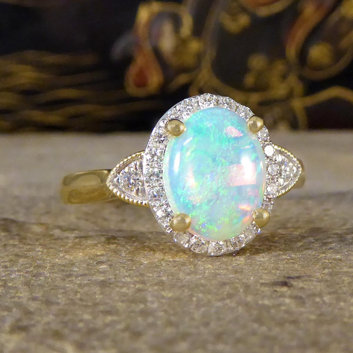 A modern and colour Opal cluster ring. This ring features an Opal in the centre showing a lovely span of colours from Oranges and Yellows to blues and Greens, in a four claw setting holding it securely into place. Surrounding the Opal are 20 small