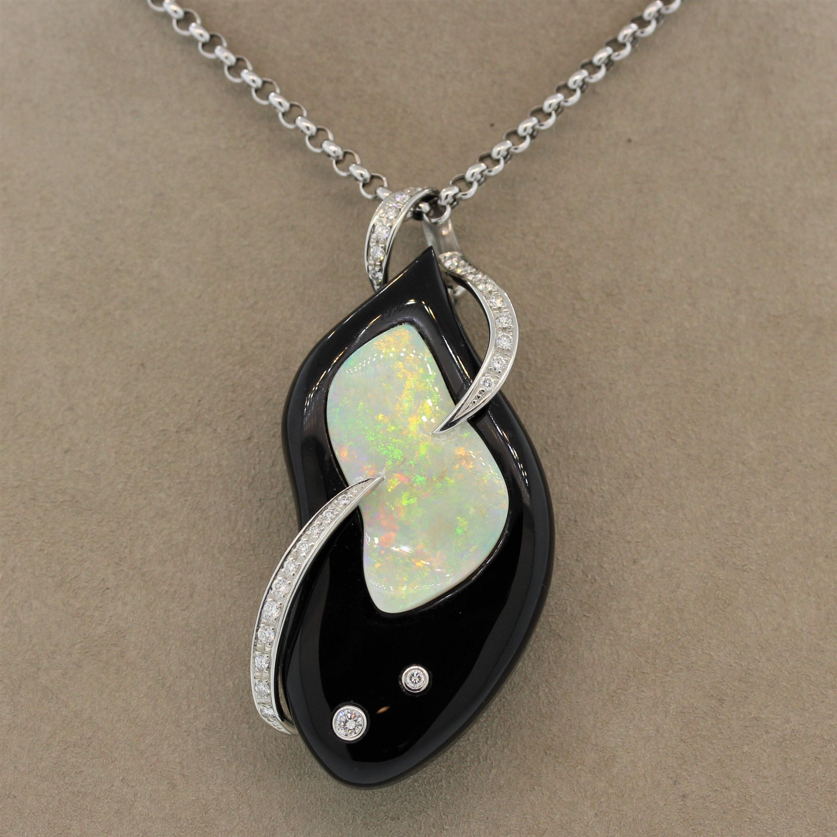 Add interest to your jewelry box with this chic platinum pendant that may also be worn as a brooch. A carved smooth piece of black onyx has a 9.94 carat opal set on top of it creating a great contrast of color between the deep black onyx and the