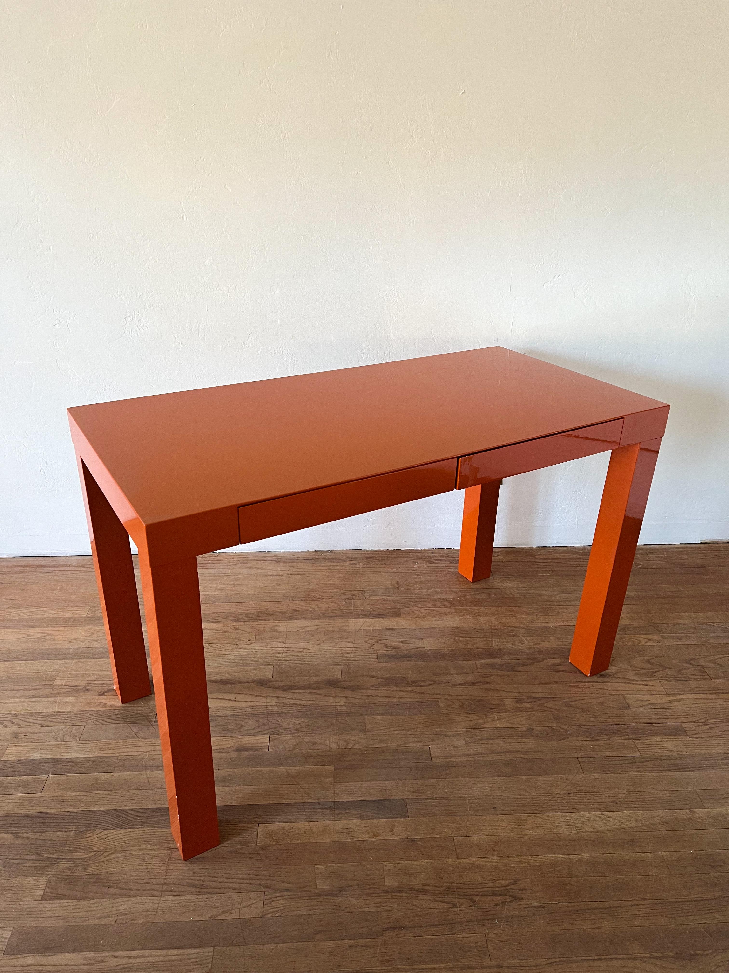 MCM lacquered orange Parsons desk with 2 drawers.
