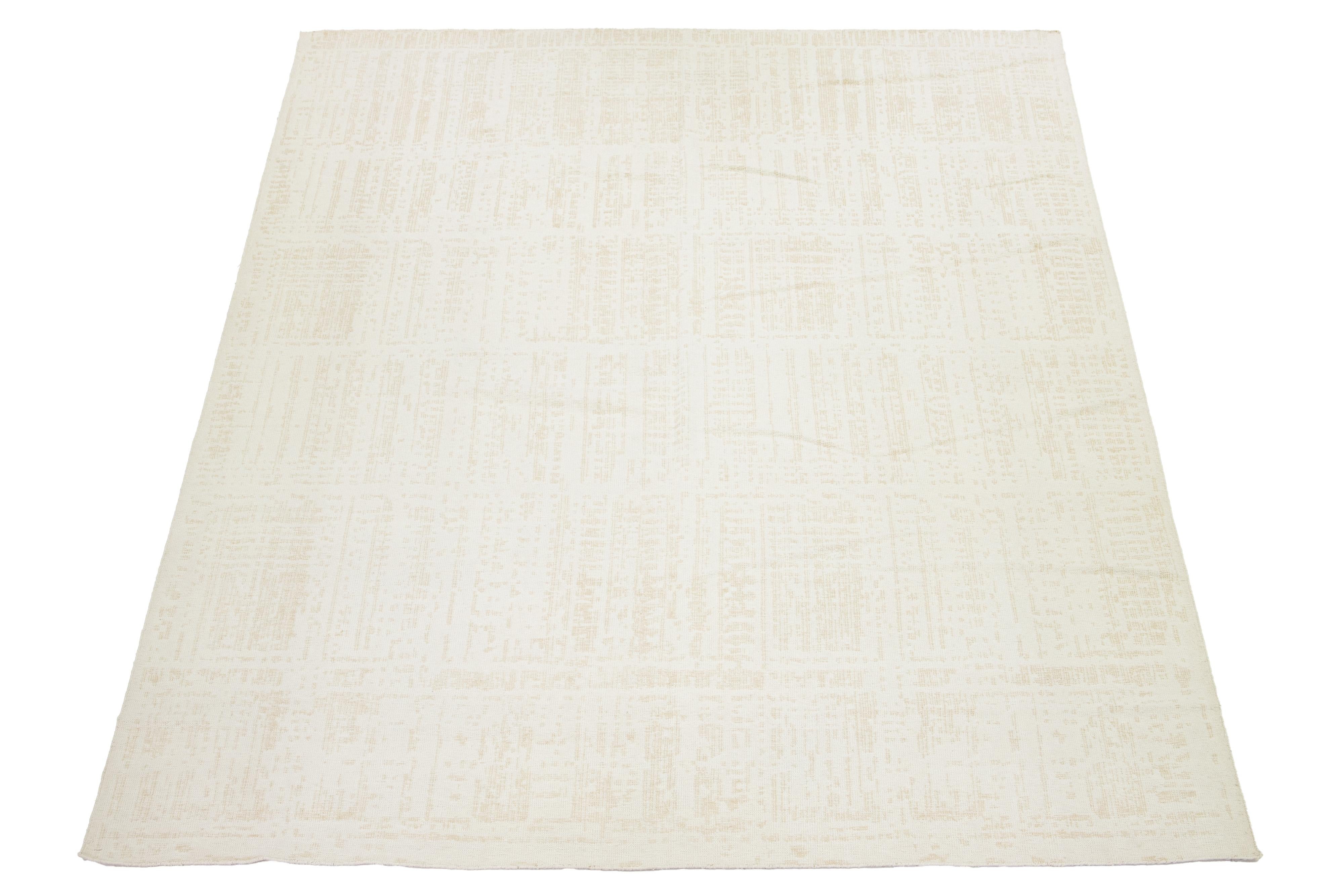 Dies ist ein schöner, handgefertigter Kelimteppich aus Wolle mit einem elfenbeinfarbenen Feld und einem beigen, minimalistischen Design.

Dieser Teppich misst 12' x 14'11