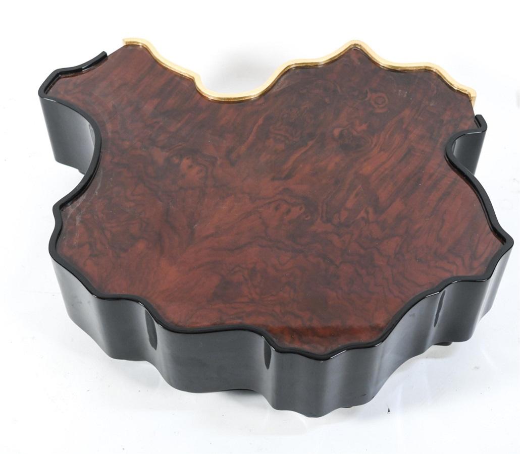 Modern organic shaped coffee table. The table has a gold gilt trim and a black lacquered frame.