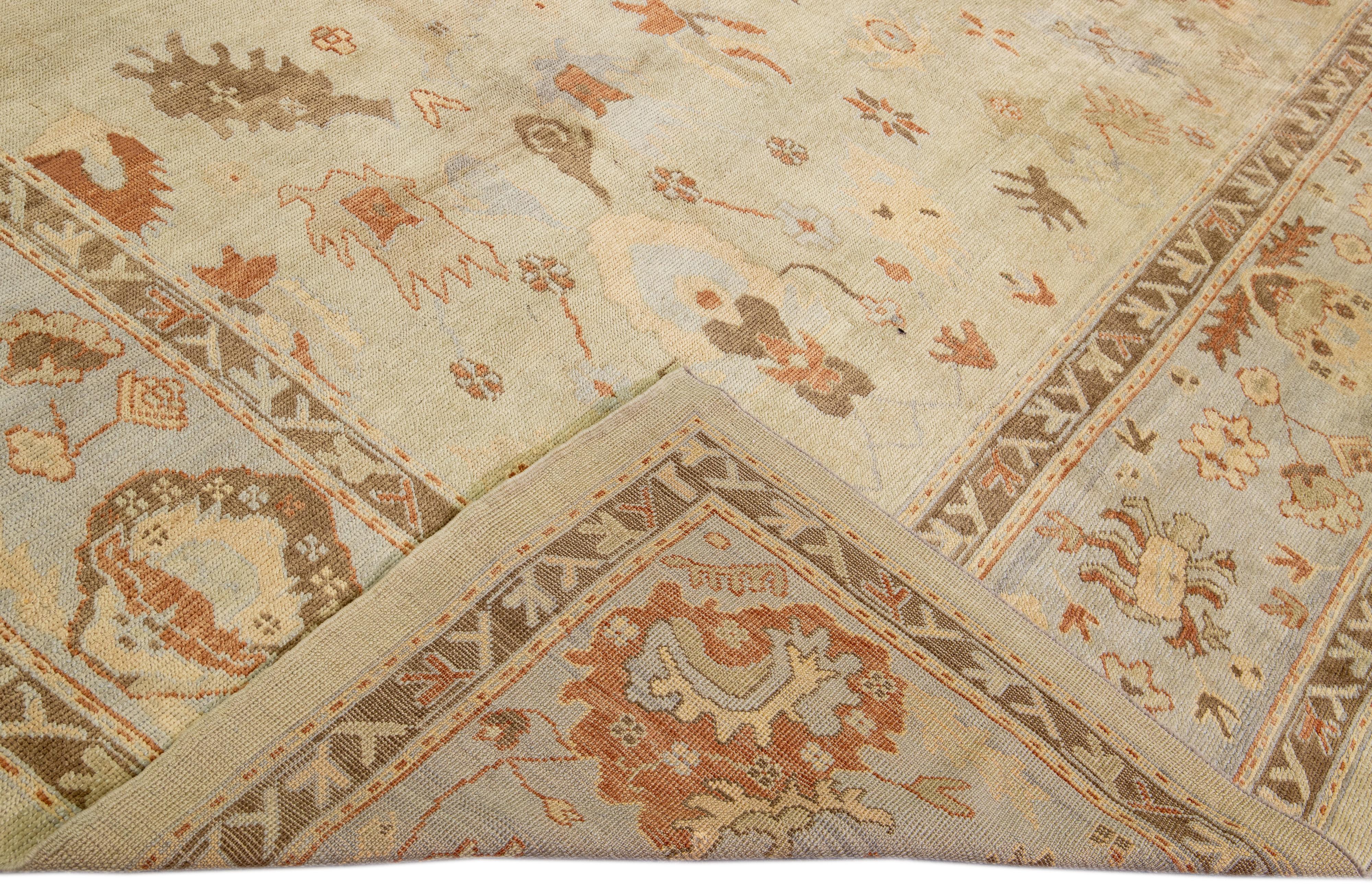 Beautiful modern Oushak hand-knotted wool rug with a beige field. This Oushak rug has blue and brown accents that feature a gorgeous floral pattern design.

This rug measures: 13'3