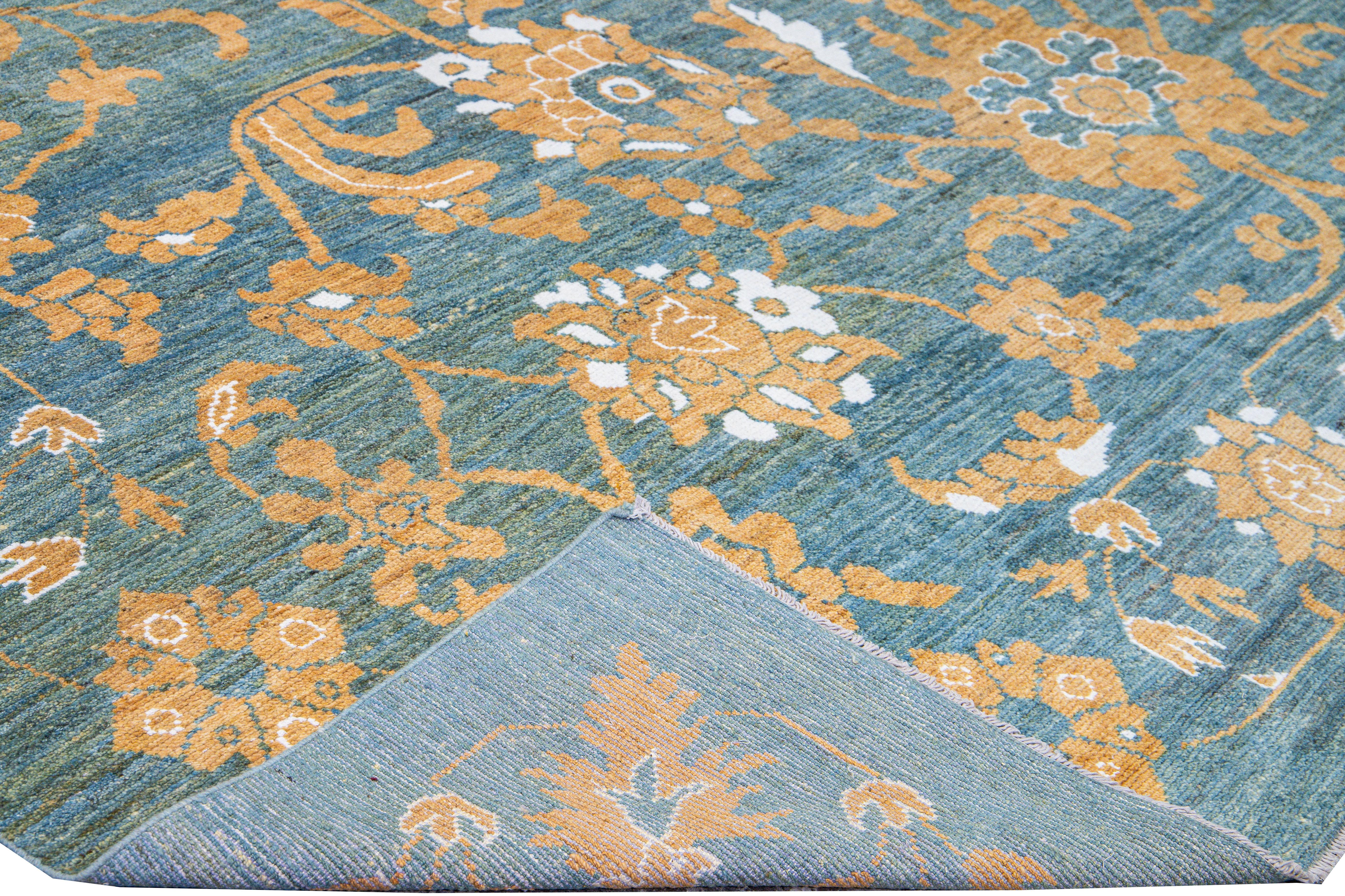 Beautiful modern Oushak hand-knotted wool rug with a blue field. This Oushak rug has orange and ivory accents in a gorgeous floral pattern design. 

This rug measures: 12'1