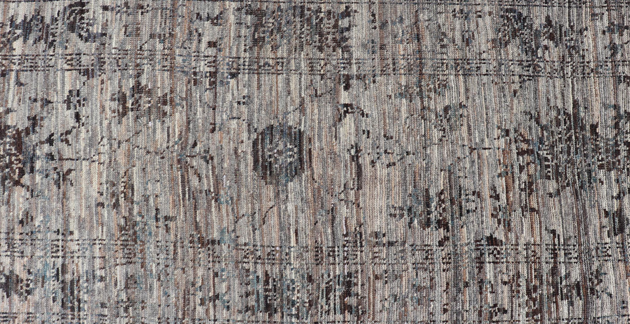 This modern casual tribal runner has been hand-knotted in wool. The runner features a modern sub-geometric floral design, and is enclosed within a complementary, multi-tiered border. The runner is rendered in charcoal, gray and earthy tones; making