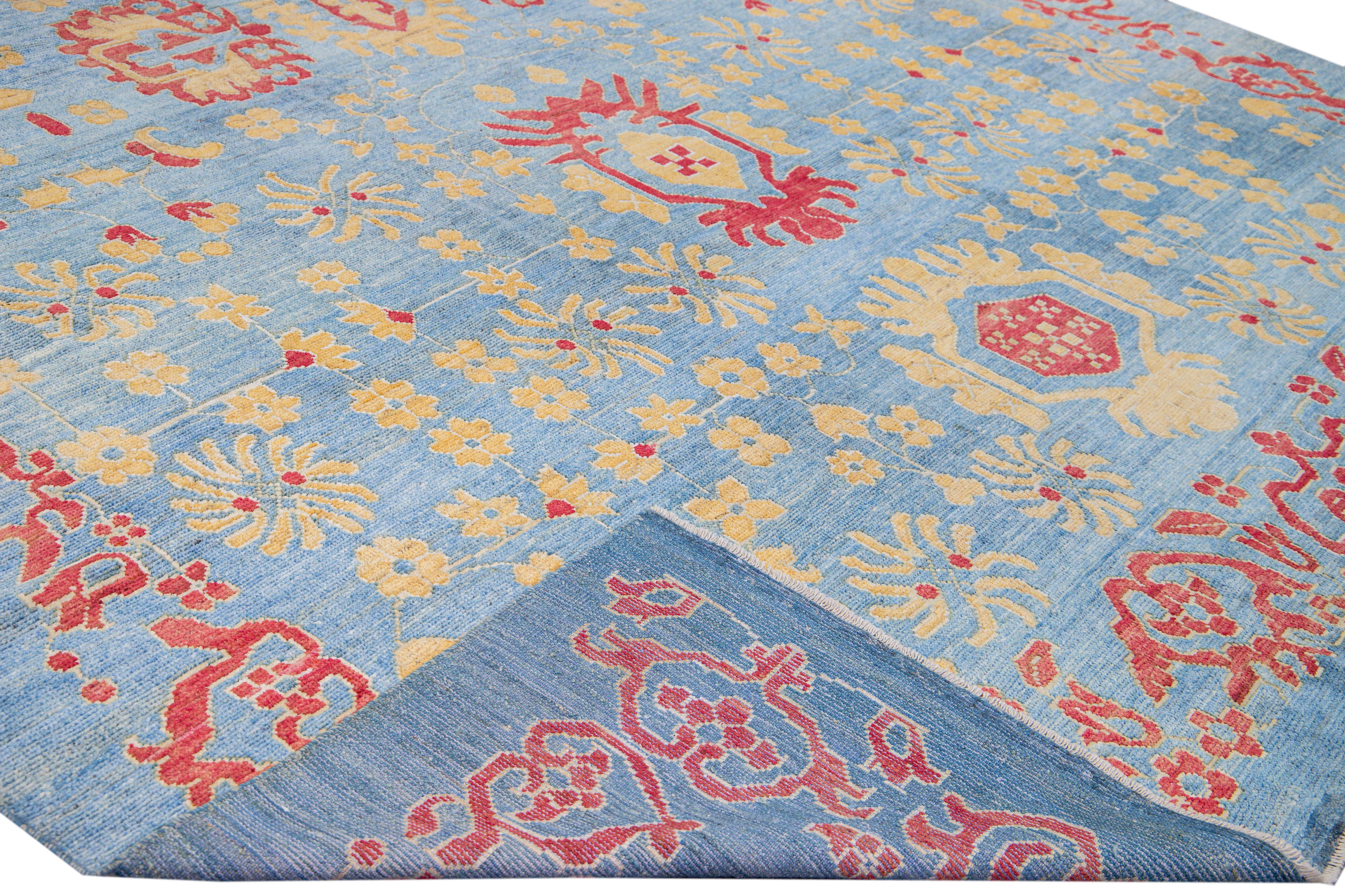 Beautiful modern Oushak hand-knotted wool rug with a blue field. This Oushak rug has a yellow and red accents layout a gorgeous tribal floral design. 

This rug measures: 12'3