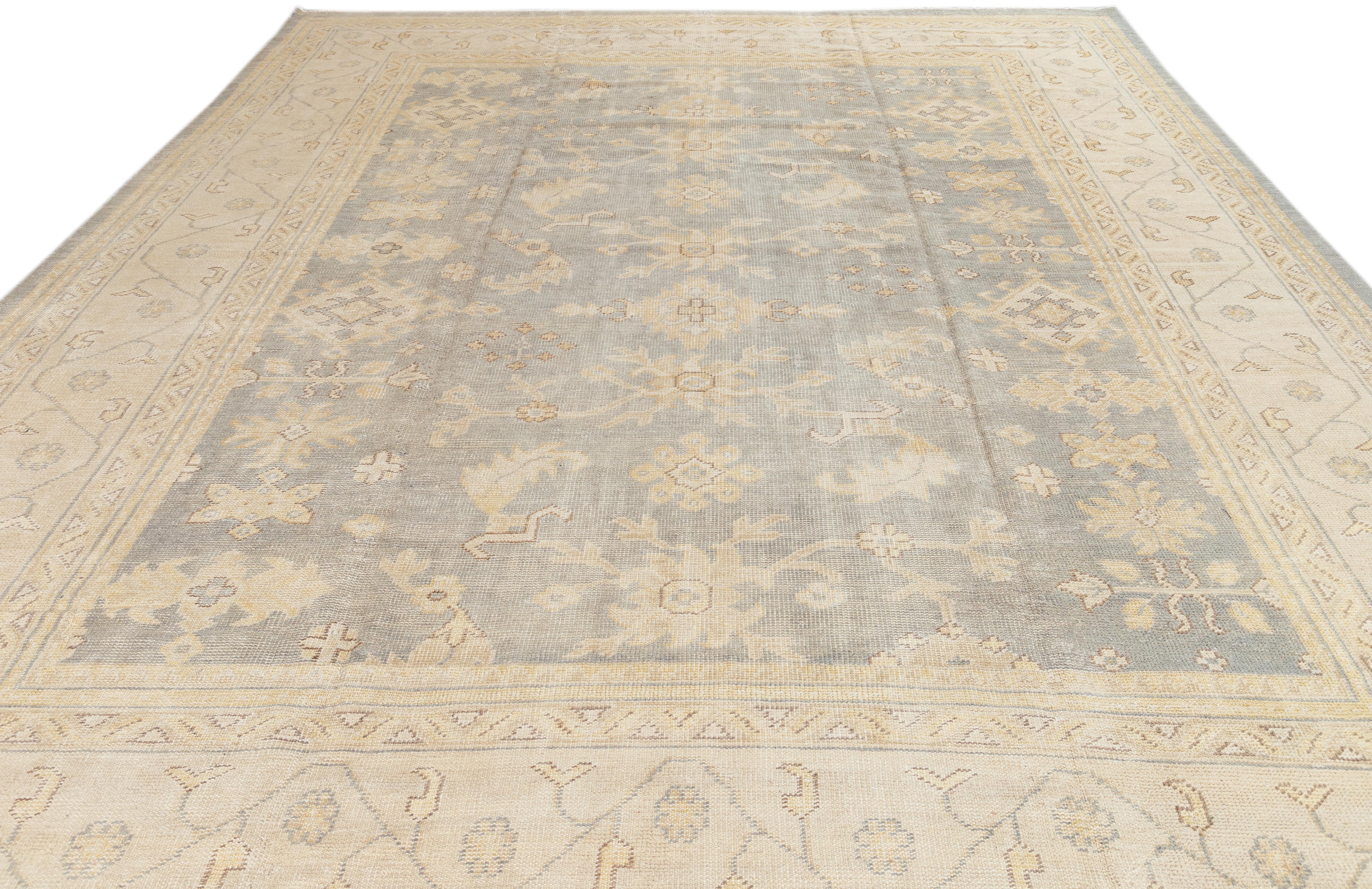 This wool rug in the Oversize Oushak Style is a stunning example of expert craftsmanship and attention to detail. Its intricate floral pattern, adorned with beige and brown accents, adds a touch of allure to any décor. The rug's base color is a