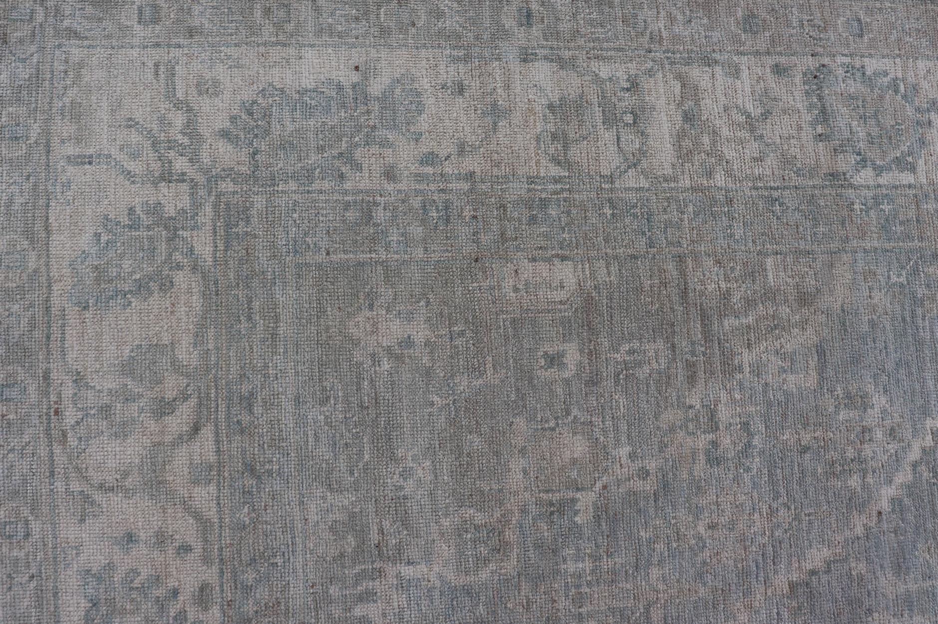 Oushak moderno con fondo azul claro y gris con medallón y motivos tribales Anudado a mano en venta