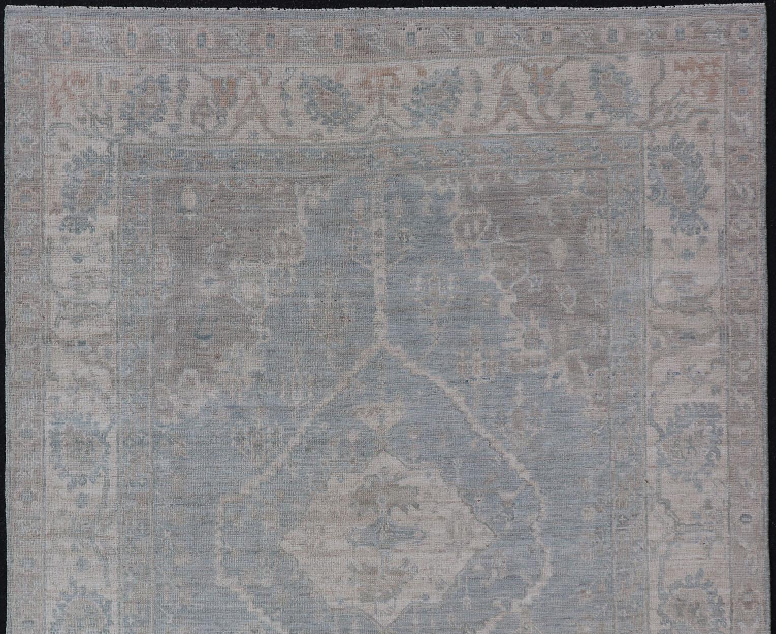 Oushak moderno con fondo azul claro y gris con medallón y motivos tribales Siglo XXI y contemporáneo en venta