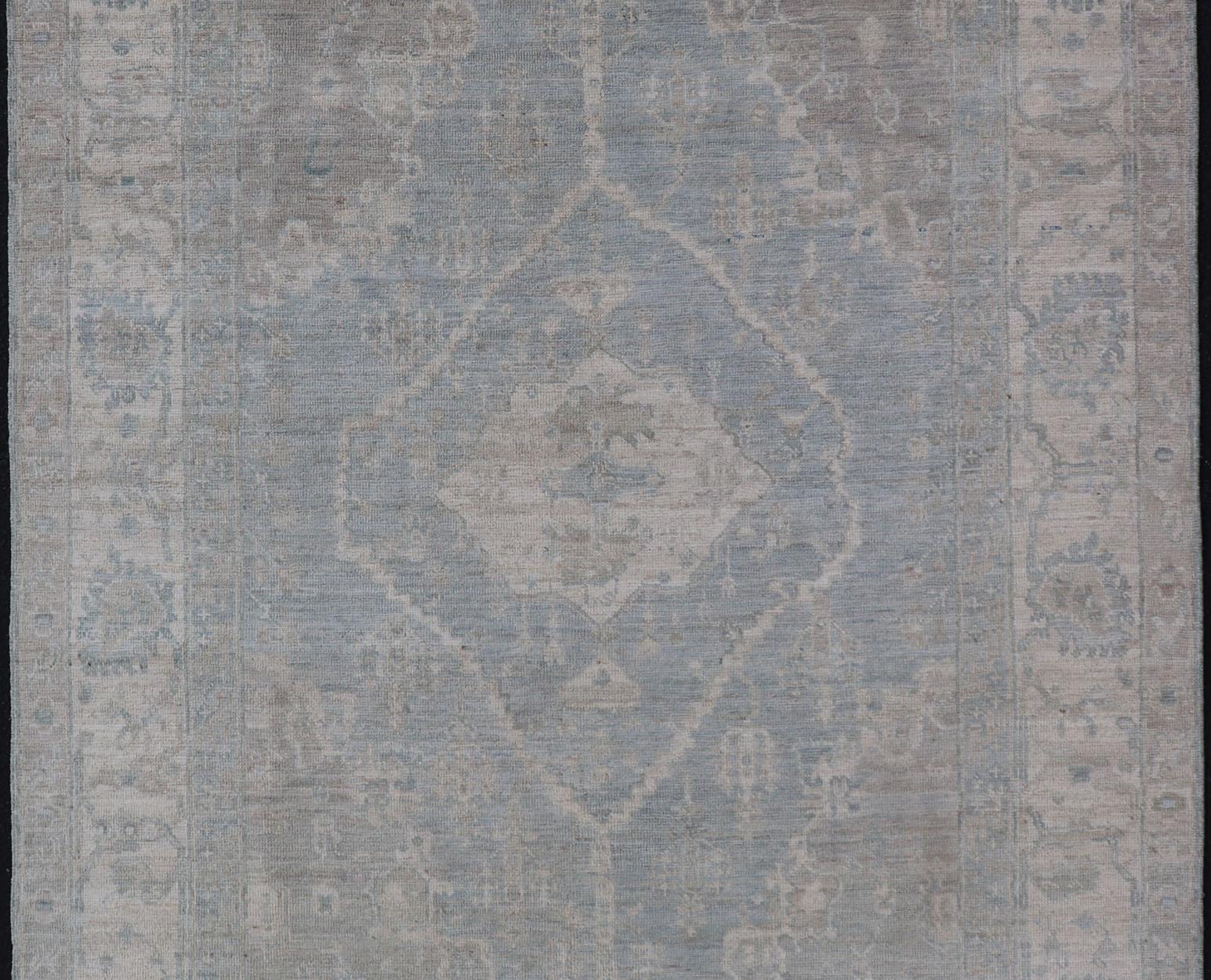 Oushak moderno con fondo azul claro y gris con medallón y motivos tribales Lana en venta