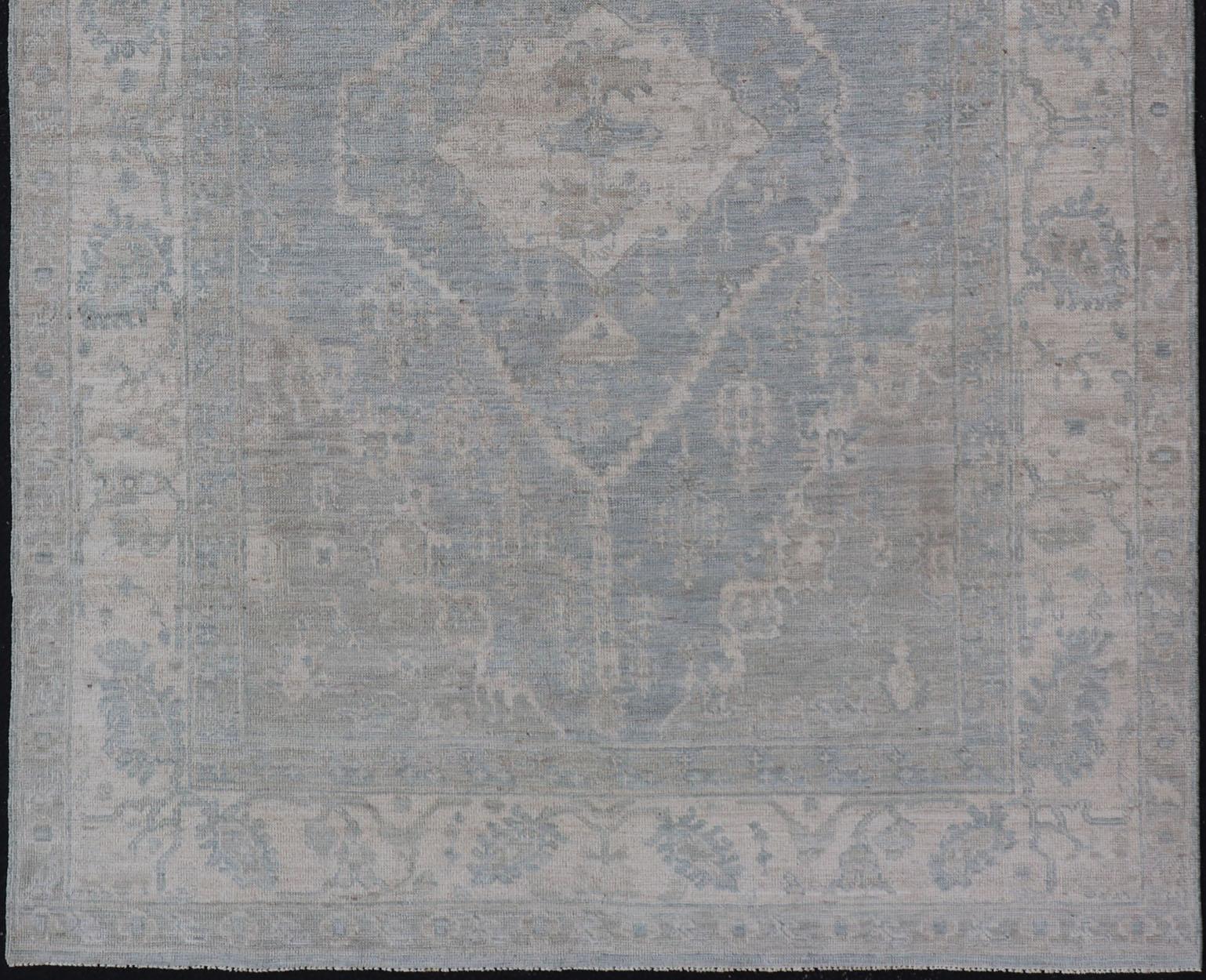 Oushak moderno con fondo azul claro y gris con medallón y motivos tribales en venta 1