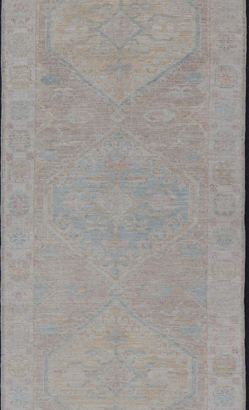 Handgeknüpftes Oushak mit hellen korallenroten und blauen Motiven auf helltaupefarbenem Hintergrund. Keivan Woven Arts: teppich AWR-3511 Herkunftsland: Afghanistan Art: Oushak Ca.: 2020

Maße: 3'0 x 12'5

Moderner, handgeknüpfter Oushak-Läufer mit