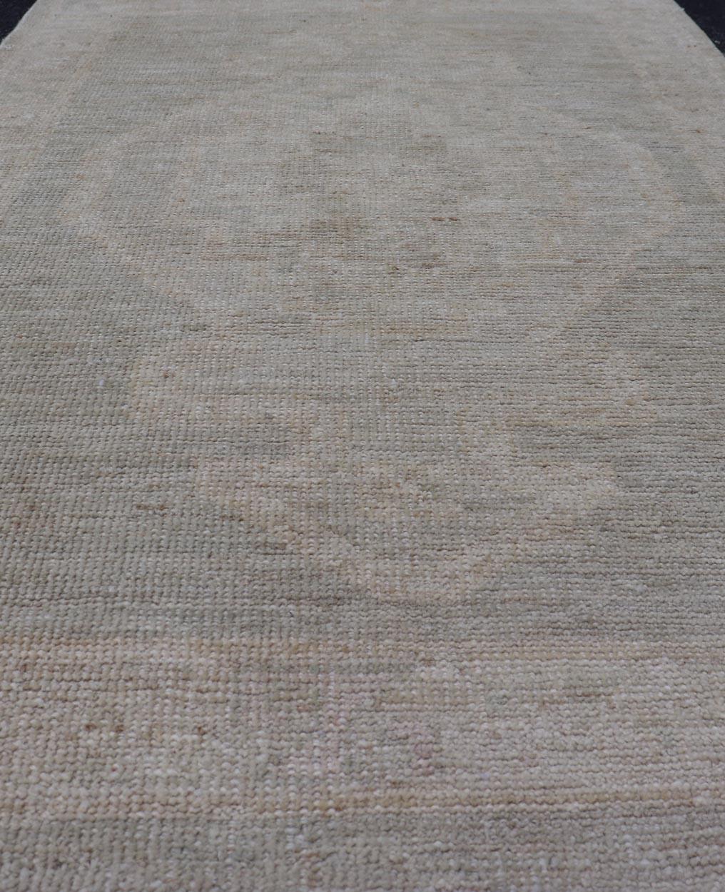 Oushak moderno con sfondo grigio sporco e un grande medaglione tribale color crema. Paese di origine: Afghanistan; Tipo: Oushak; Design: Medaglione, Medaglione tribale, All-Over; Keivan Woven Arts: tappeto AWR-16772. 21° secolo. 
Misure: 2'8 x 4'3