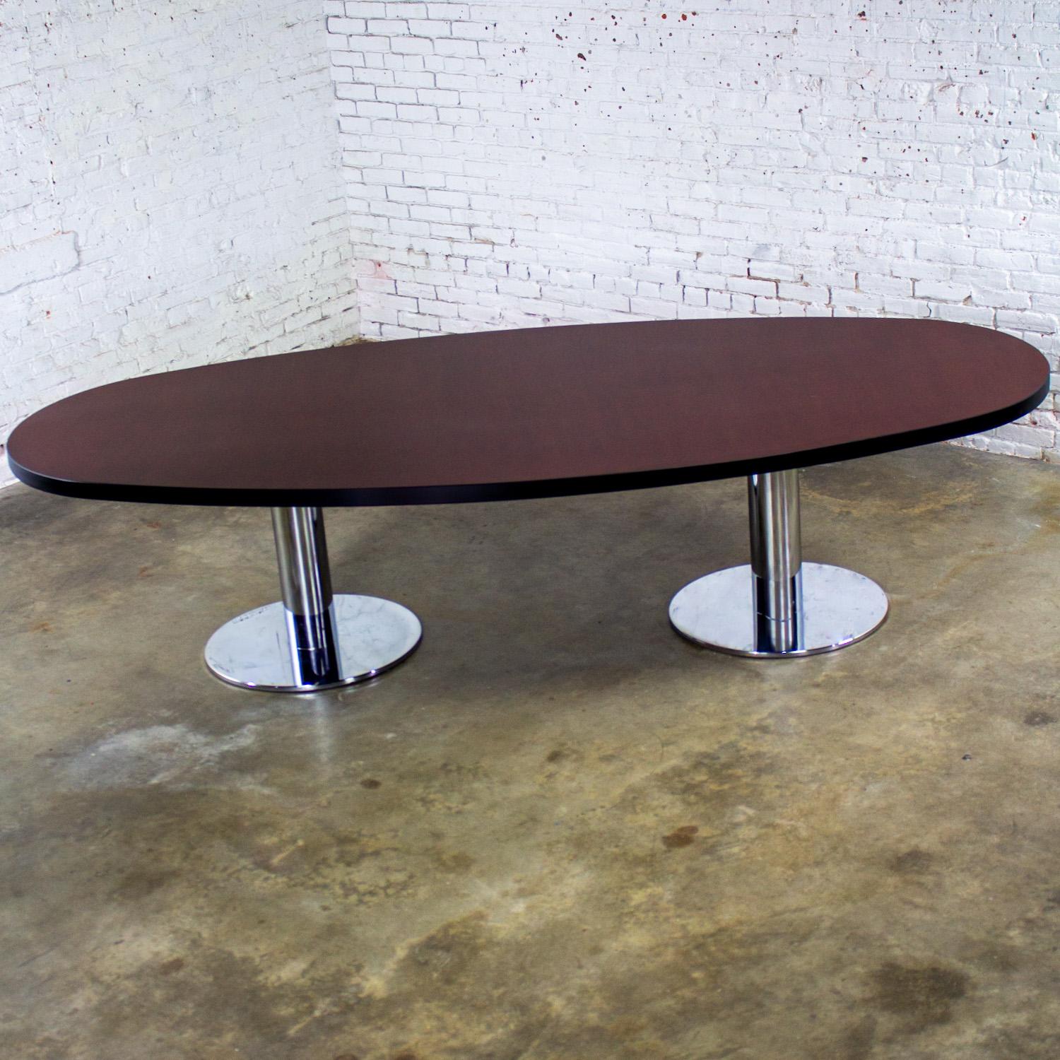 Magnificent Late 20th Century Modern oval dining or conference table comprised of a rosewood veneer top, black painted edges, and a chrome cylindrical double pedestal base. Beautiful condition, keeping in mind that this is vintage and not new so