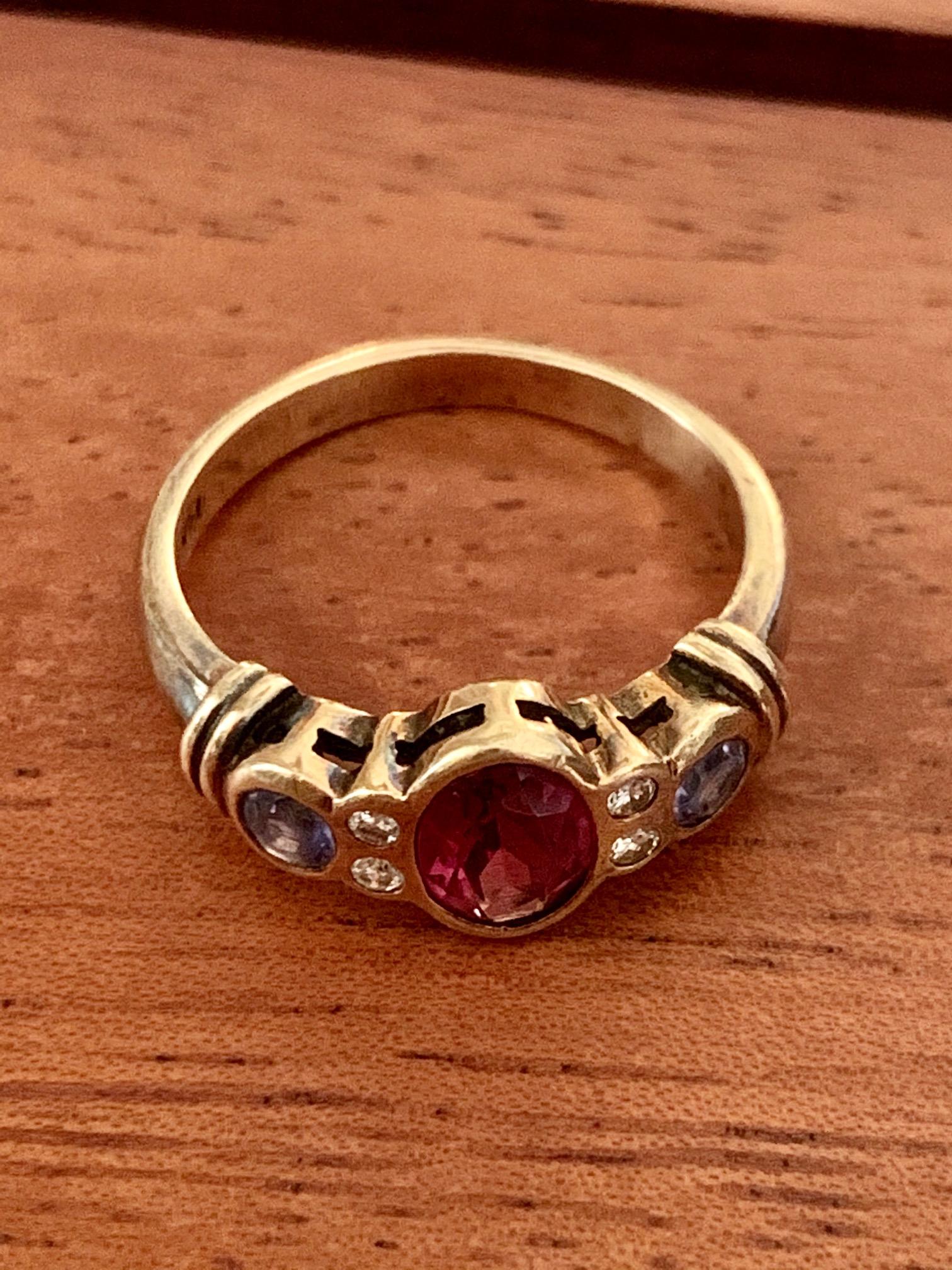 This modern ring features one 7 x 5mm oval Rhodolite Garnet center stone and two 3mm Tanzanite side stones, along with 4-1.5mm brilliant cut side Diamonds.

Size: 6 1/4
Weight:  3.7 grams