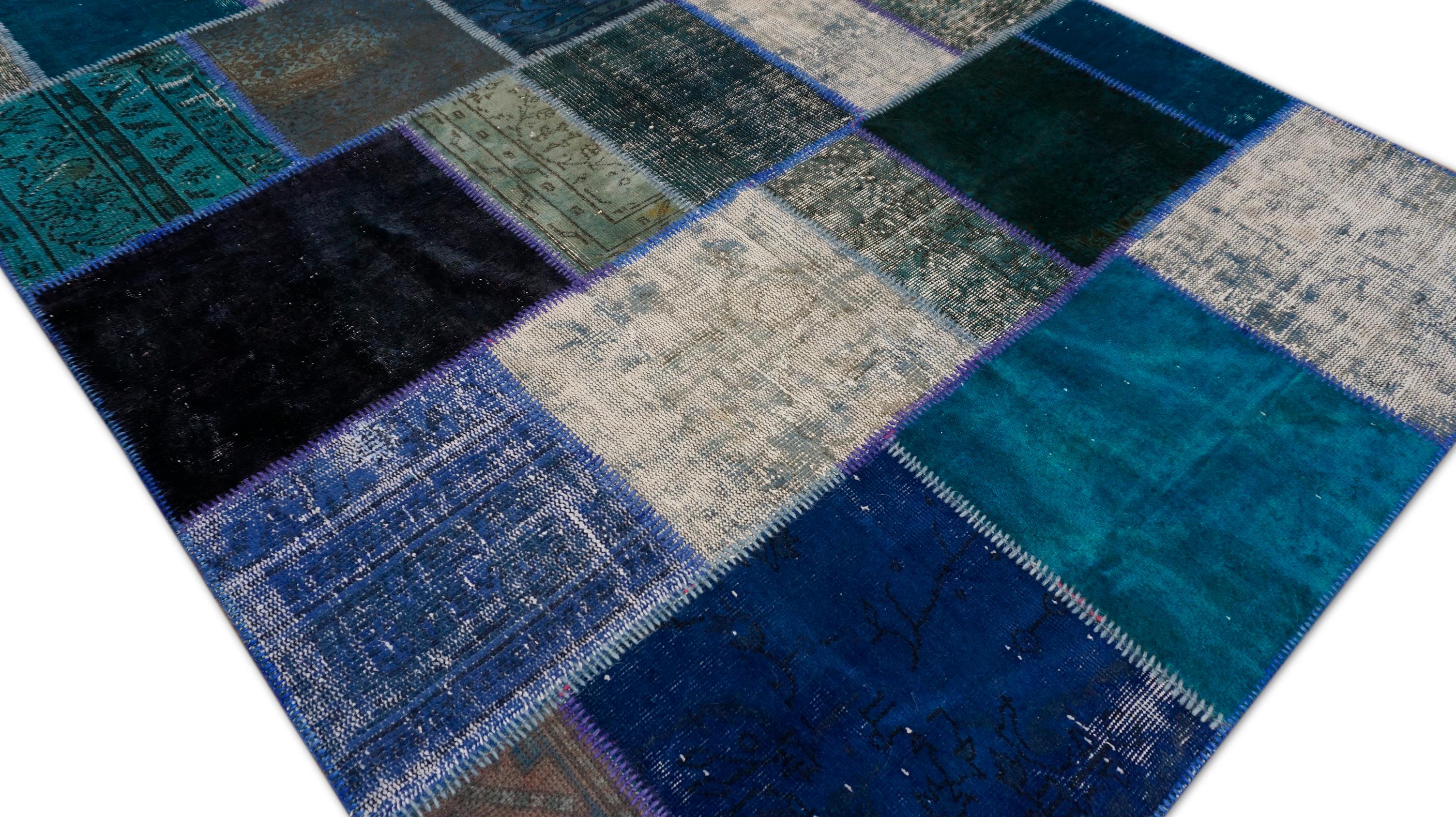 Dieser exquisite, gefärbte Flickenteppich ist aus Wolle handgewebt und kunstvoll aus wiederverwendeten Vintage-Teppichen zusammengesetzt, wobei jeder Block einzeln in auffälligen Teal-, Türkis-, Elfenbein- und Holzkohle-Tönen gefärbt ist. Der
