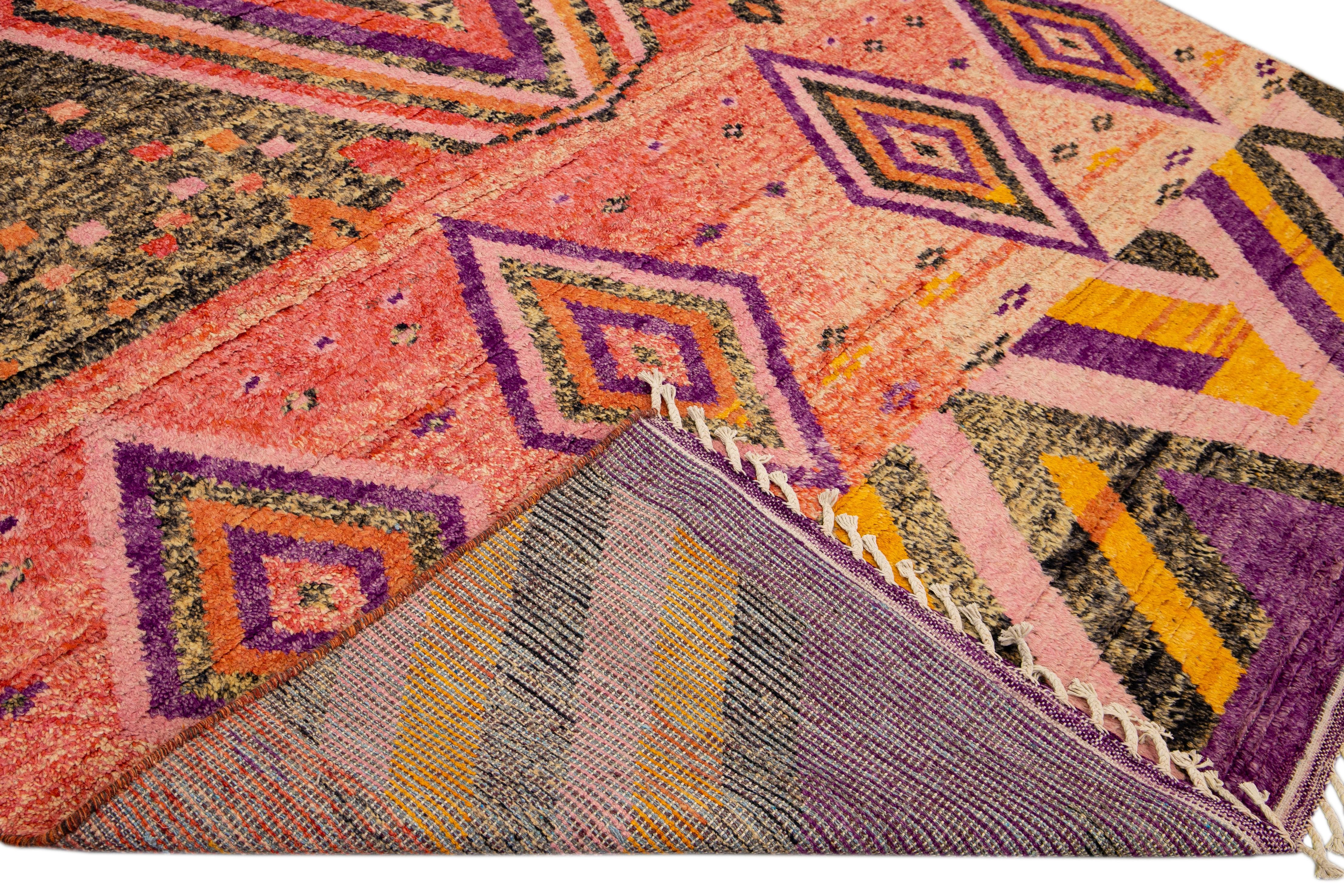 Beautiful Moroccan style handmade wool rug with peach and purple field. This Modern rug has orange, gray, and yellow accents and beige fringes featuring a gorgeous all-over boho geometric design.

This rug measures: 9'4
