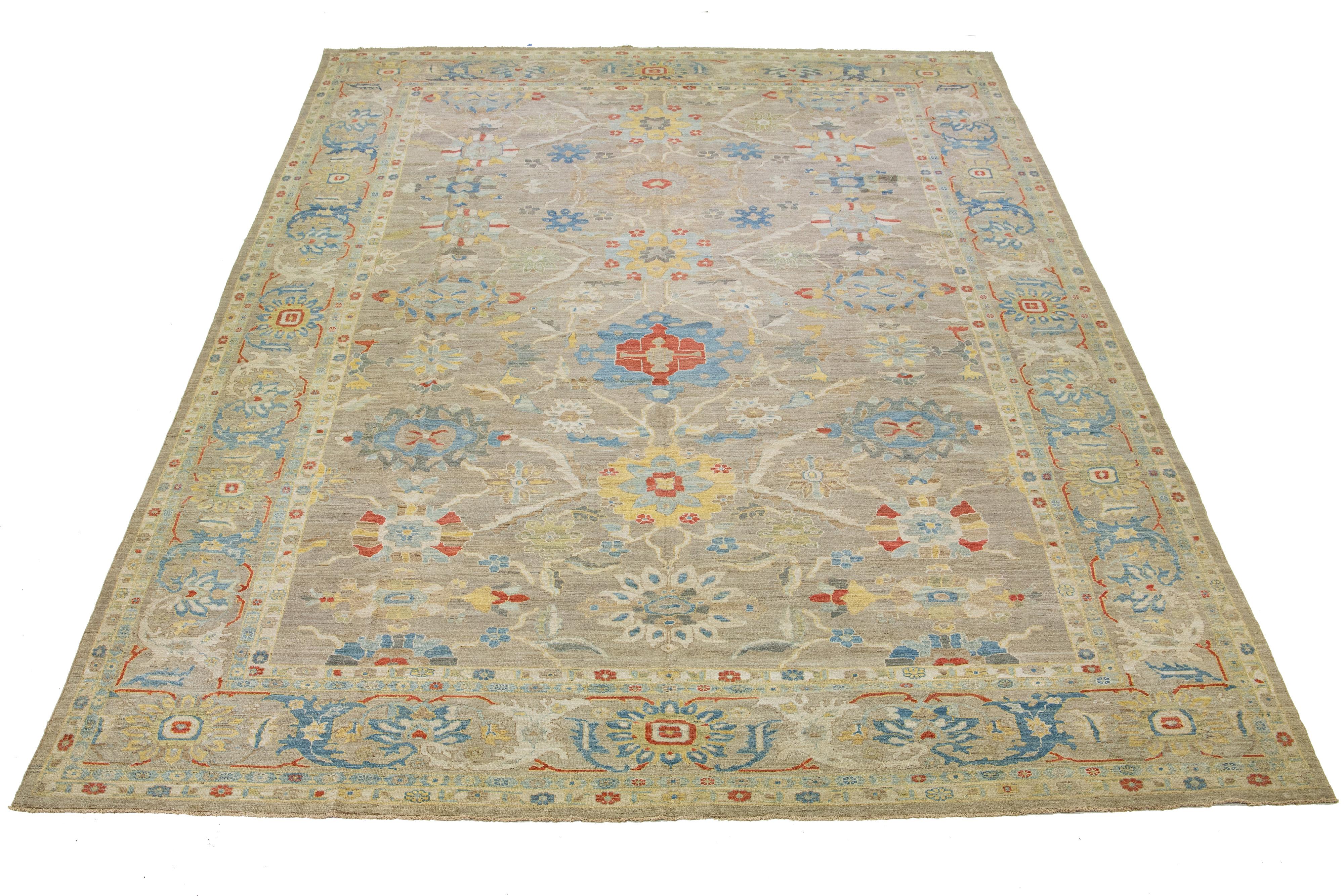This oversized Sultanabad classic style has been meticulously transformed into a contemporary masterpiece. Crafted with great care, this magnificent wool rug has a light brown field. It has an all-over floral motif. To enhance its elegance, it