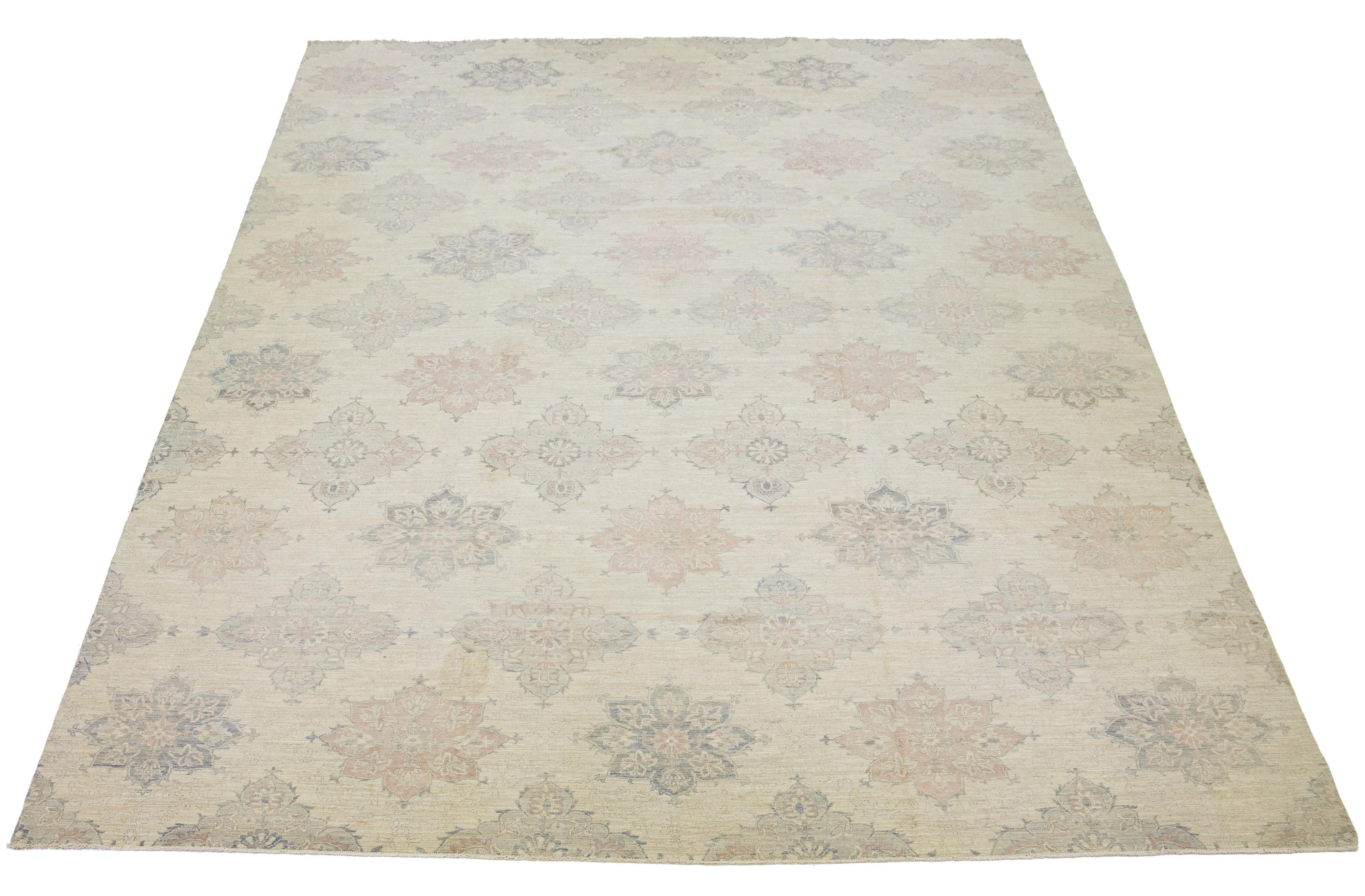 This oversized hand-knotted wool rug showcases a beige field. It's designed with a stunning allover floral pattern and accented with gray and peach hues in a Transitional allure.

This rug measures 11'10