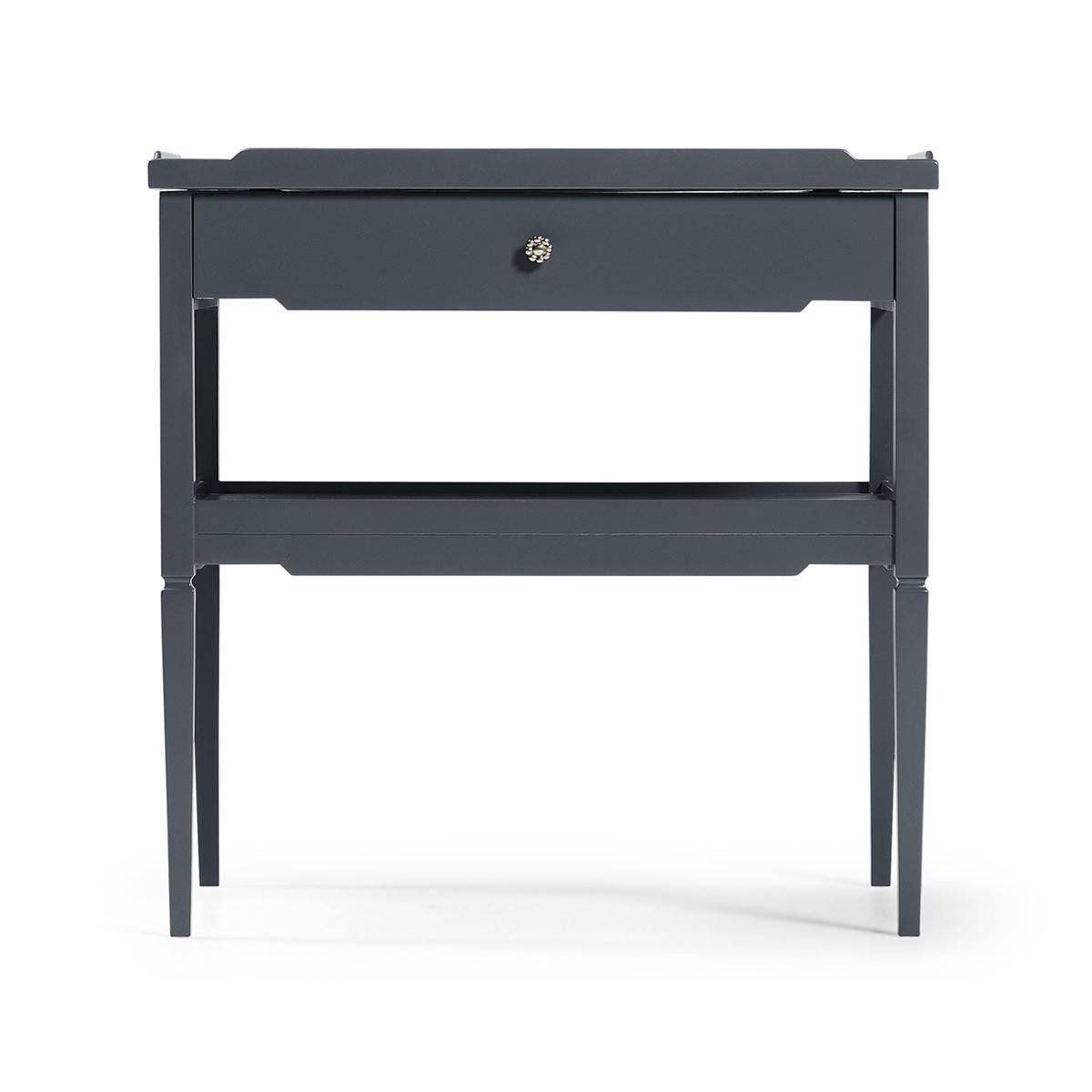 Modern painted side table with a hale navy lacquered finish, with a lipped top that doubles as a pull out tray, single drawer lined with a zany blue and white print, power supply access and cord management and a lower shelf for oversized items.