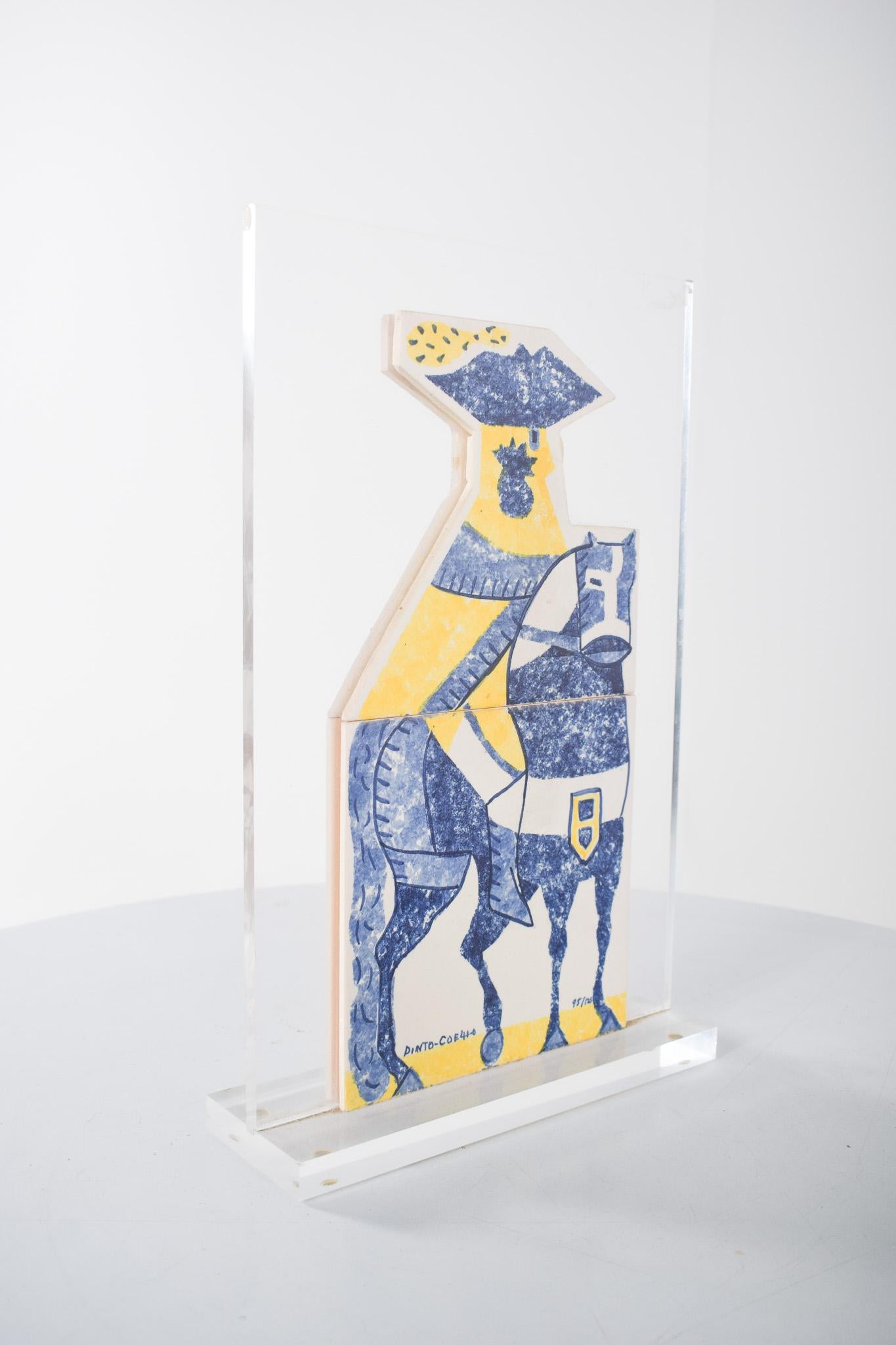 Scultura pittorica di Luís Pinto Coelho, in piastrelle. Composto da due piastrelle tagliate e dipinte, montate su una base acrilica trasparente, rappresenta un cavallo stilizzato nei toni del blu e del bianco con dettagli geometrici e uno scudo al
