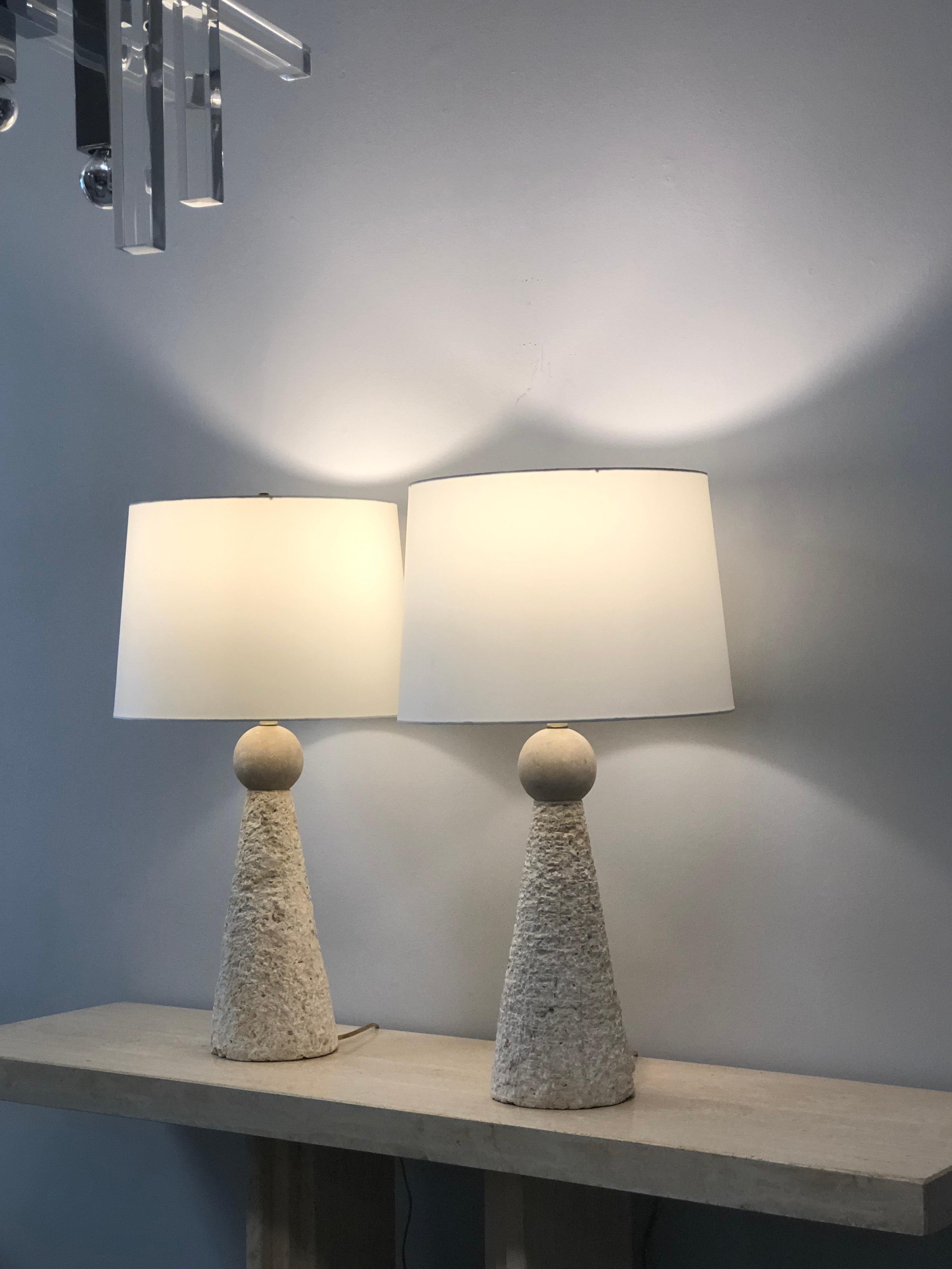 A pair of table lamps. The bases are chipped stone on wood crowned by a slate sphere. Simple designed yet elegant and modern. Measures: Shades are 12
