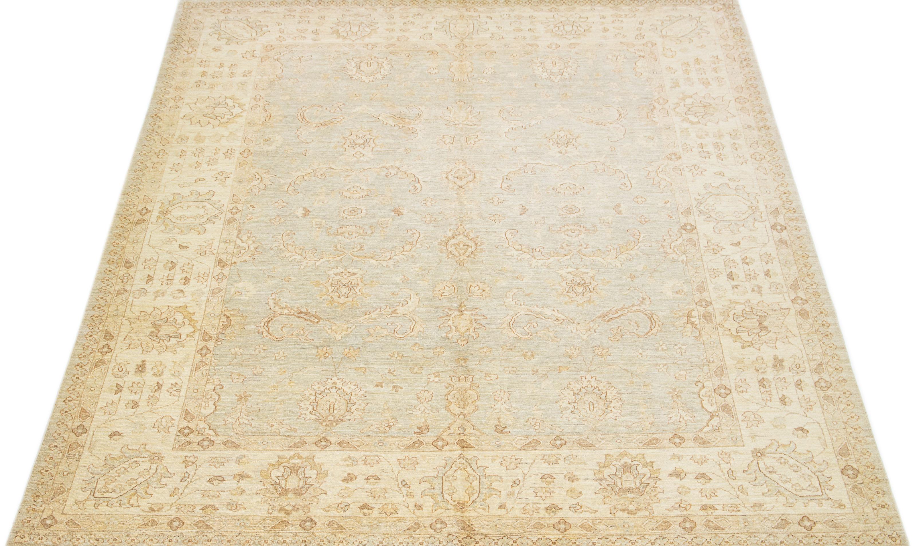 Ce tapis contemporain en laine de Peshawar, fait à la main, présente une  fond gris avec d'élégants reflets beiges. Il arbore un motif floral intemporel.

 Ce tapis mesure 8'1