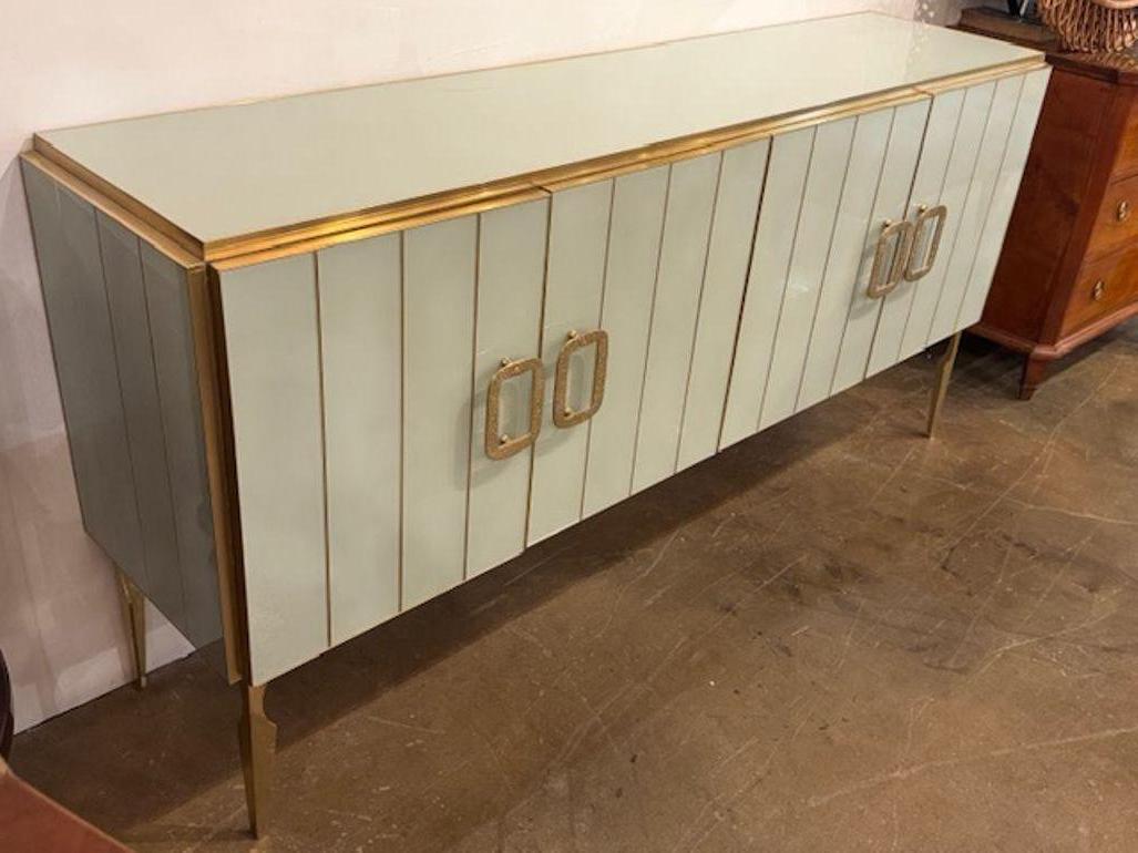 The modern pale green Murano glass sideboard with brass accents exudes a contemporary style, making it a unique and stylish addition to any home décor. Beautiful clean lines  add a touch of elegance to the piece, making it a standout piece in any