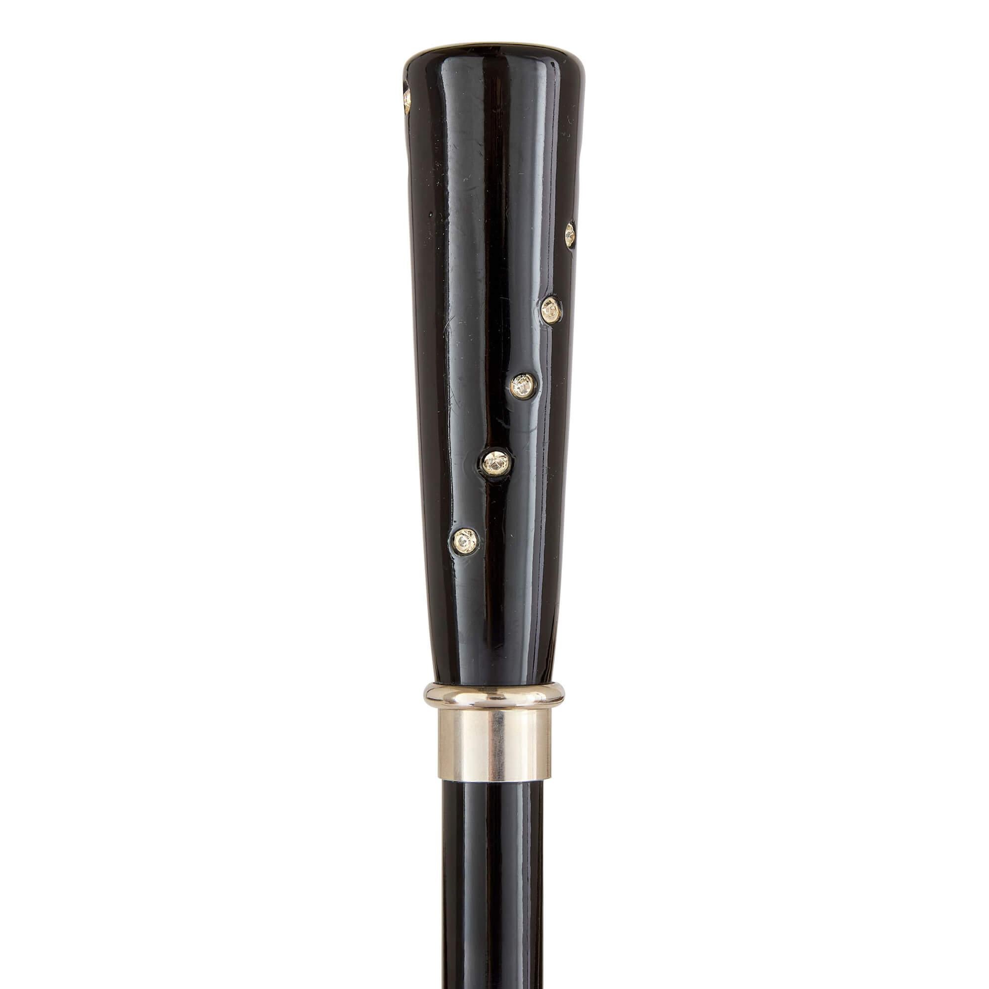 Canna moderna in legno con gemma in pasta 
Continentale, 20° secolo 
Altezza 92 cm, diametro 3,5 cm

Questo elegante bastone da passeggio, realizzato nel XX secolo, emana un'eleganza raffinata e minimalista che ricorda figure leggendarie della moda