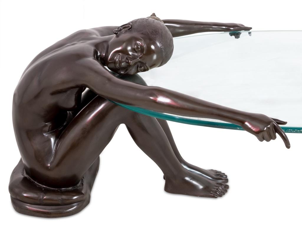 Table basse figurative moderne en bronze patiné, la figure nue assise sur un coussin, les bras tendus tenant un plateau de verre ovale. 22