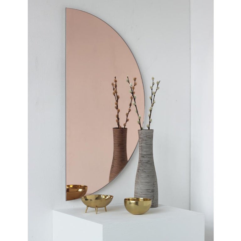 Original and minimalist half-moon rose gold tinted frameless mirror with a floating effect. Quality design that ensures the mirror sits perfectly parallel to the wall. Designed and made in London, UK. 

Each piece is fitted with professional plates