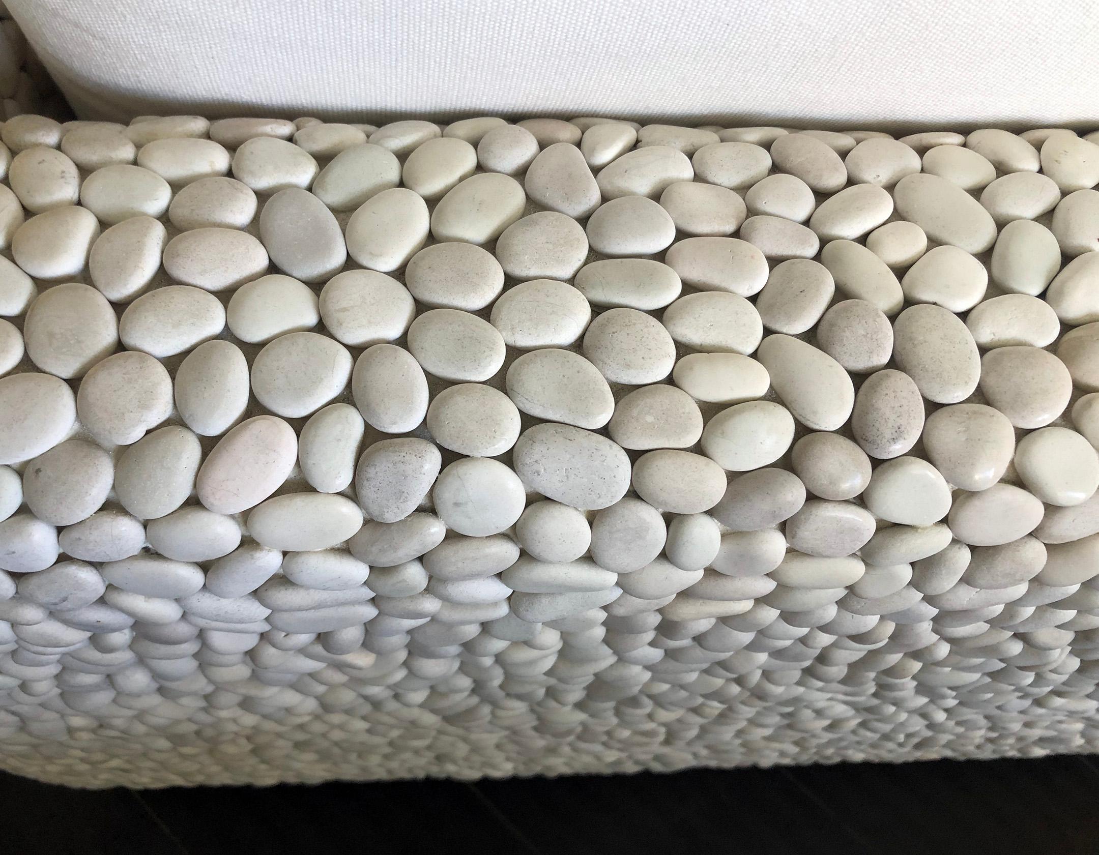 Stylish, modern, and comfortable. This indoor/outdoor lounge chair is entirely clad in naturally white river pebbles. It is upholstered in a linen colored Sunbrella type duck fabric. A wonderful statement piece that would look incredible in any