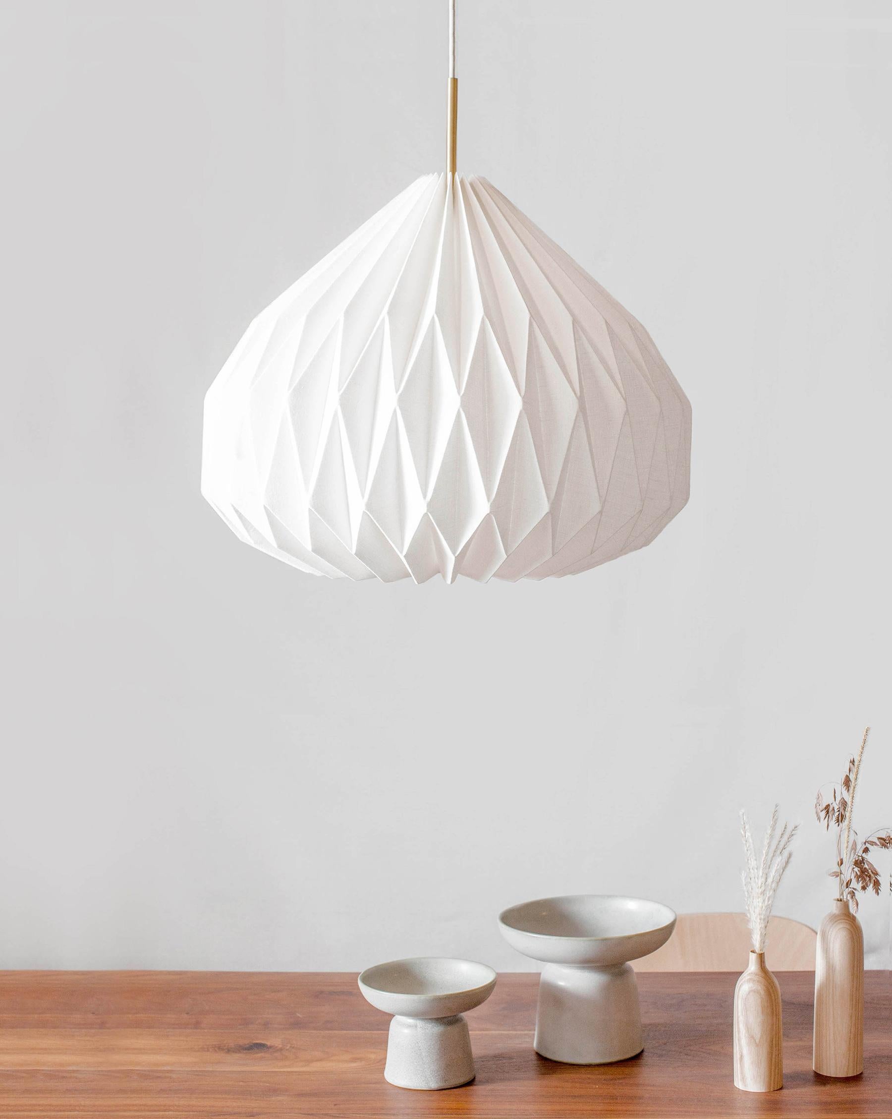 This modern-style pendant light will add an interesting and functional work of art to your interior.
Made of hand-folded laminated line fabric,  the pendant shade provides soft ambient lighting while maintaining a delicate and refined aesthetic with